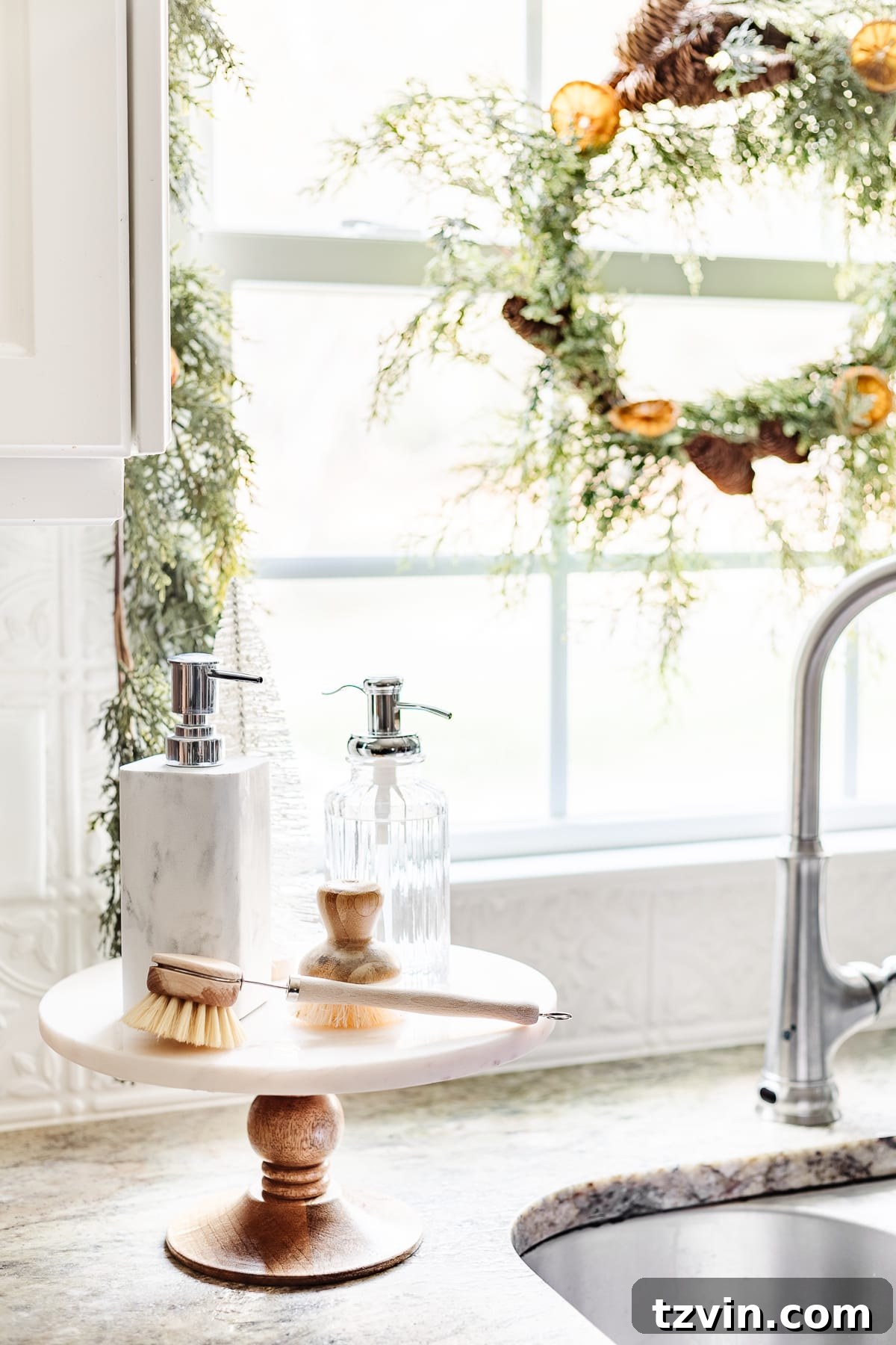 cake stand next to kitchen sink with soaps and bottle brush tree