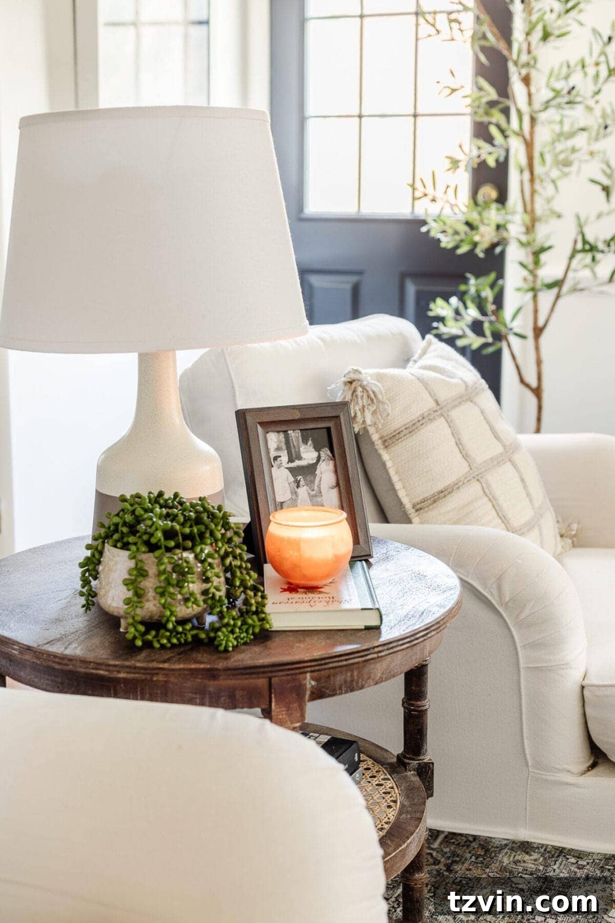 My Favorite Winter Living Room Touches 7 End table featuring cozy winter decor with a potted green plant, a candle, and art, adding warmth to the room.