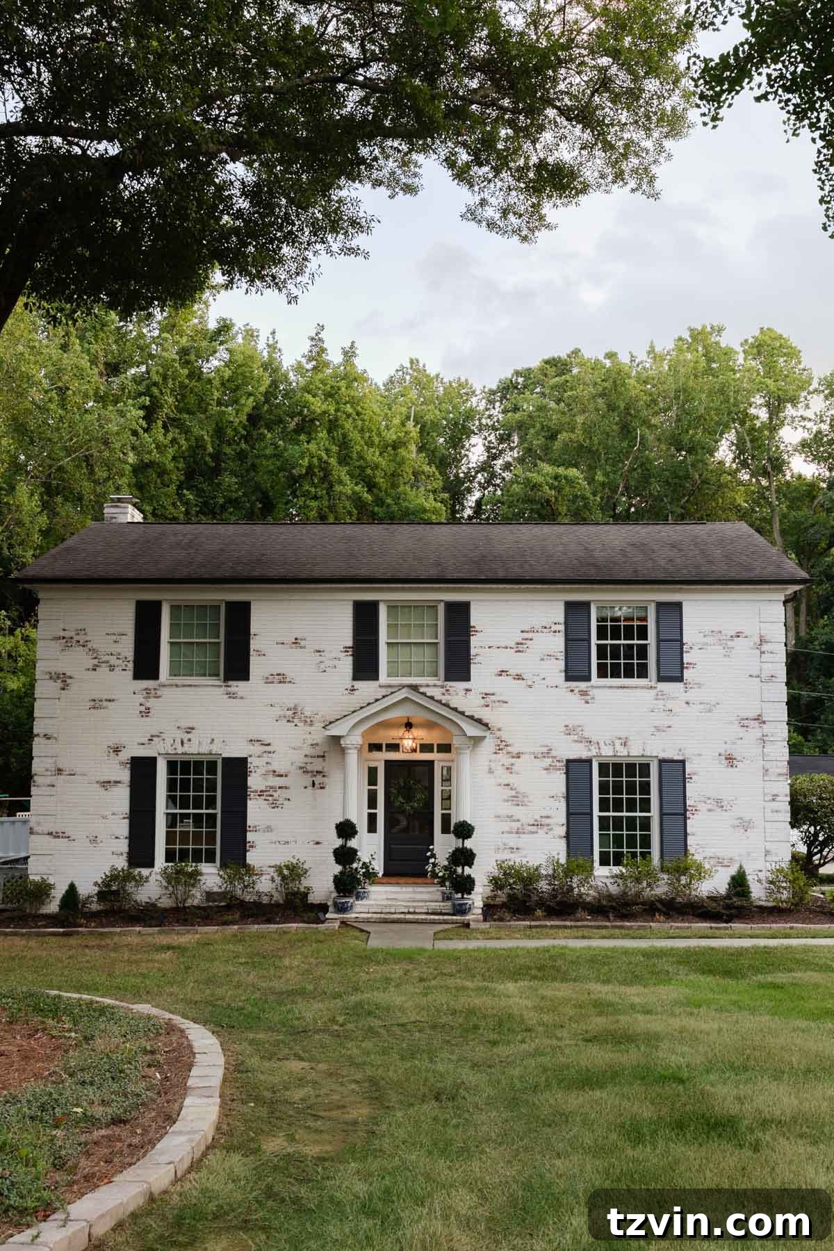 Colonial limewashed brick house exterior with a new front door.