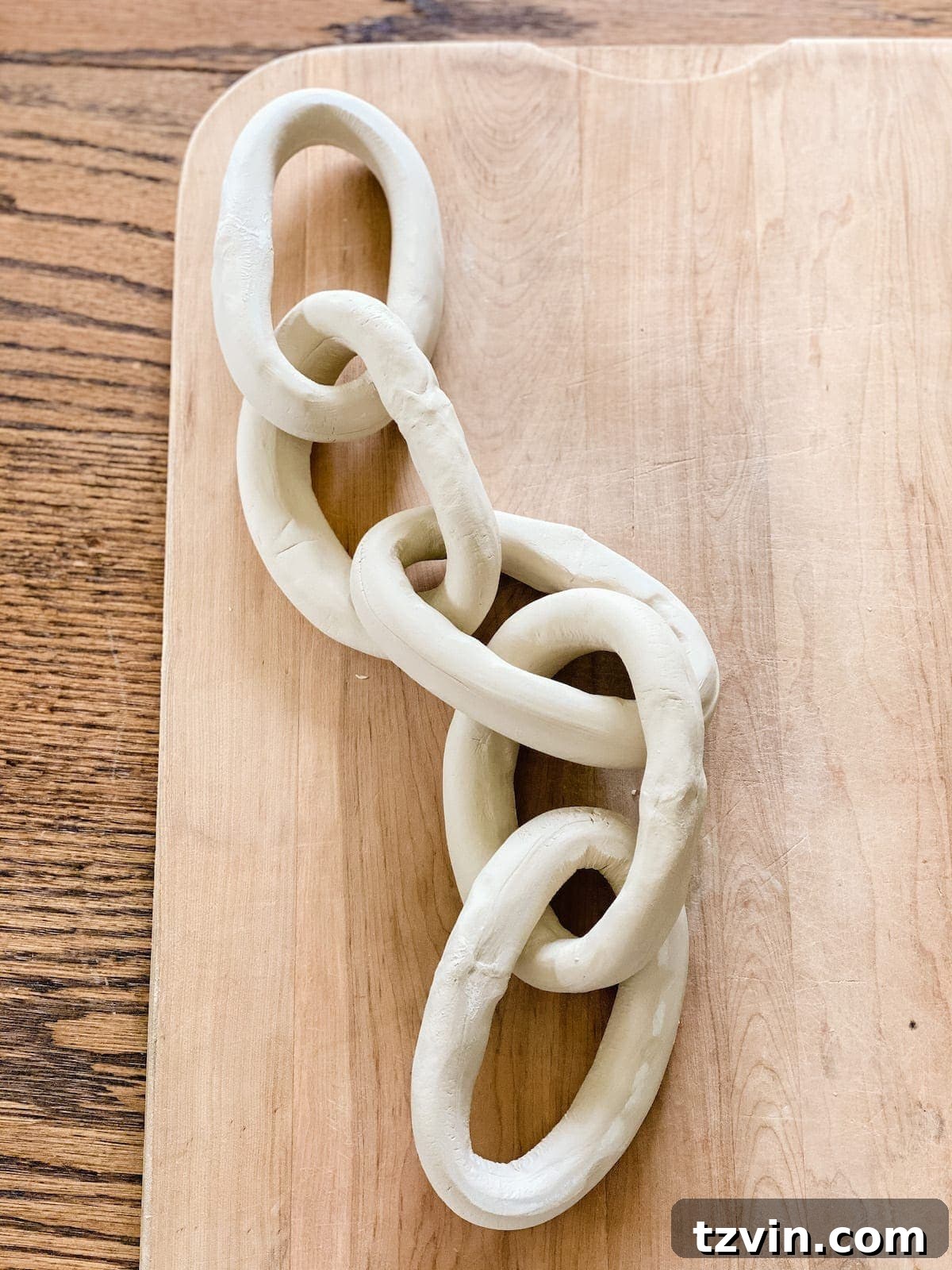 Create Decorative Chains from Air Dry Clay 6 Two air dry clay links connected to form a chain, with a third link being added through a dried link.