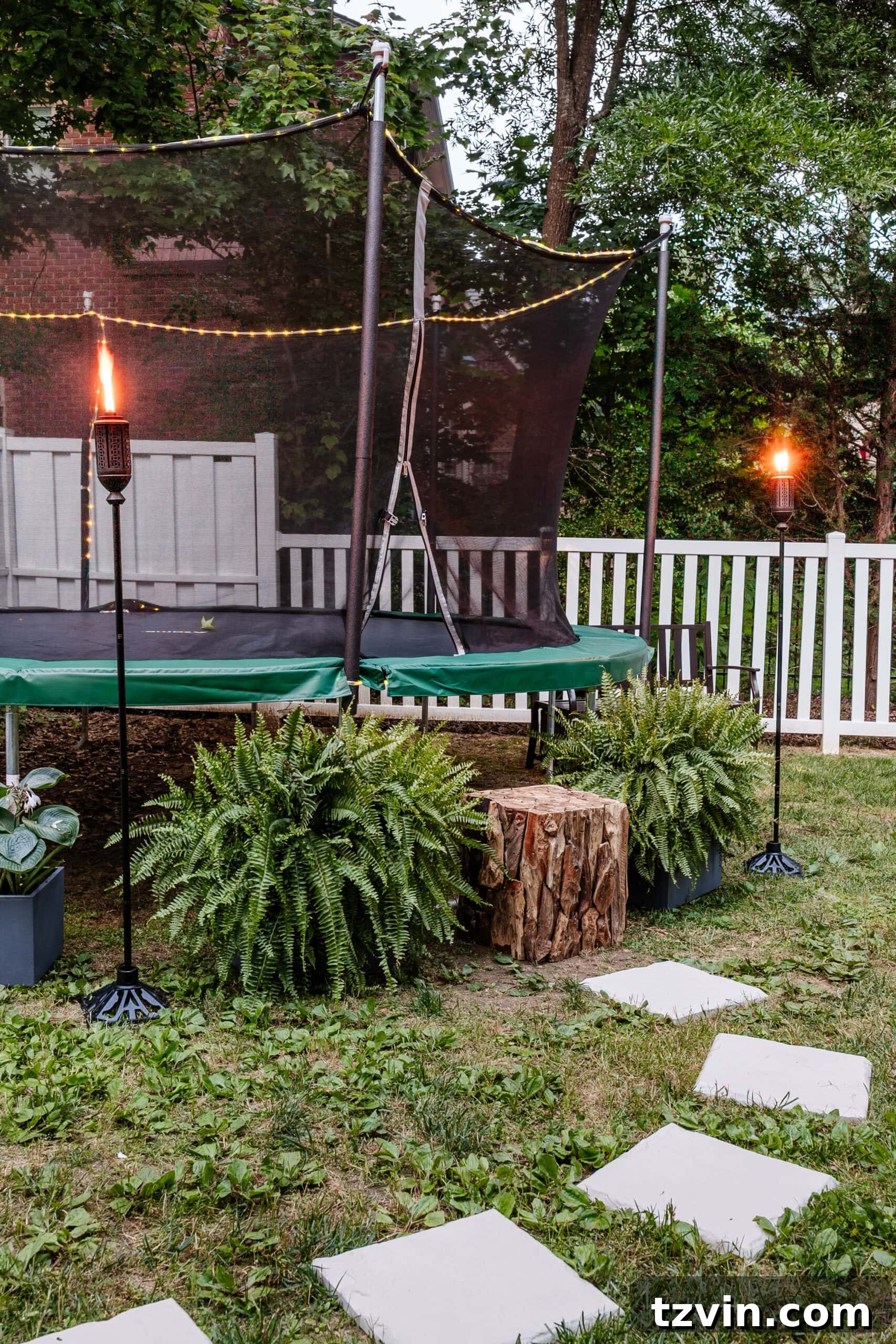 trampoline with tiki torches around it to repel mosquitoes in the yard
