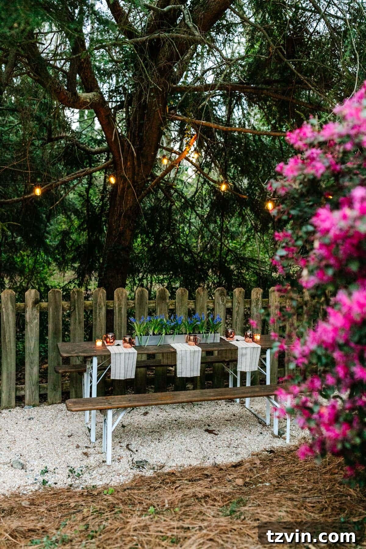 A serene DIY beer garden setup featuring a folding table on pea gravel, illuminated by charming string lights for evening dining.