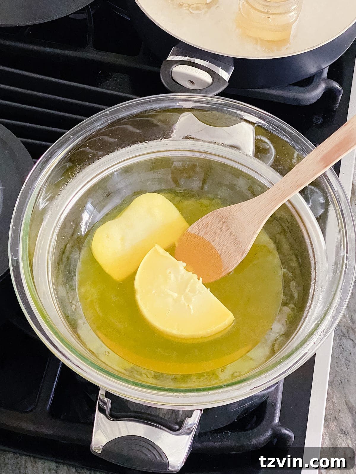 Close-up of molten candle wax being stirred in a bowl over a double boiler, ready for pouring.
