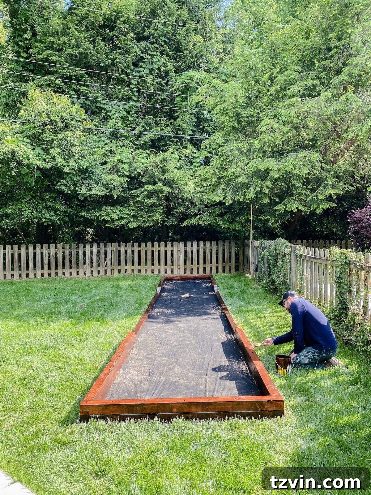 applying final waterproofing stain to bocce court frame