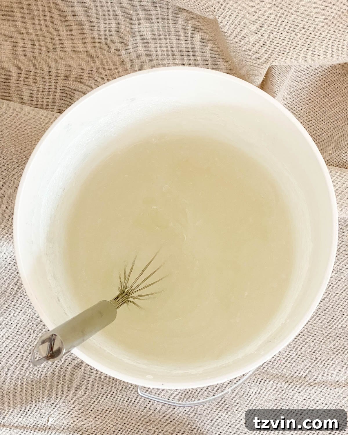 Create a Designer Look: Wallpapering Inside Picture Frame Molding 5 Mixing wallpaper paste in a bucket with a whisk, ensuring a smooth and consistent mixture for application.