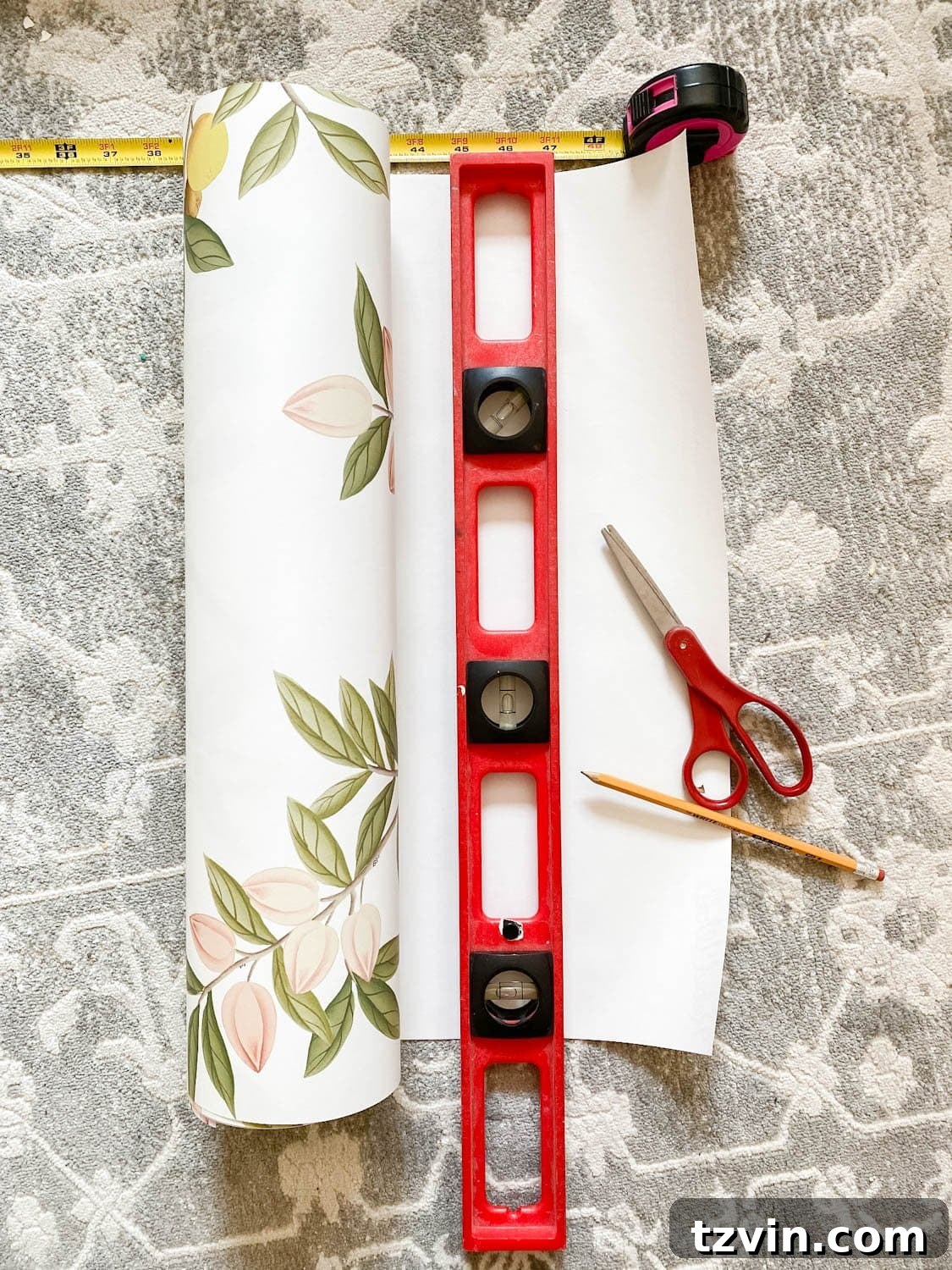 Create a Designer Look: Wallpapering Inside Picture Frame Molding 7 Measuring and cutting the first strip of unpasted wallpaper on a clean surface, allowing extra length for trimming.