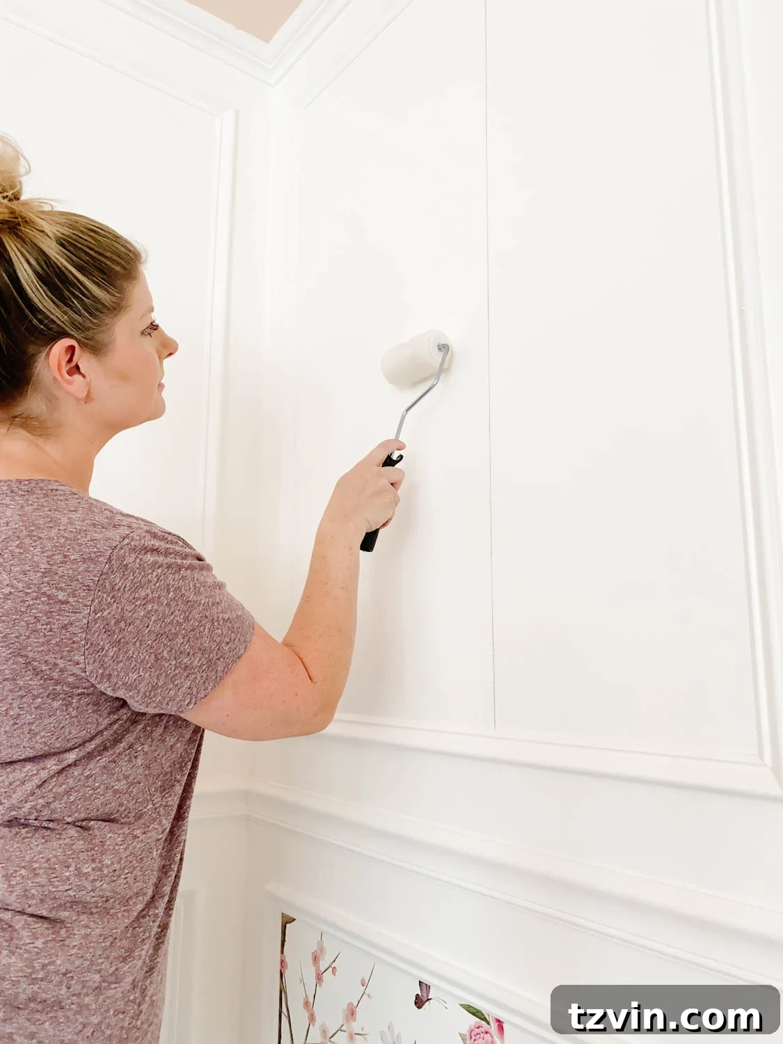 Create a Designer Look: Wallpapering Inside Picture Frame Molding 9 Using a mini paint roller to apply an even layer of wallpaper paste to the wall inside picture frame molding.