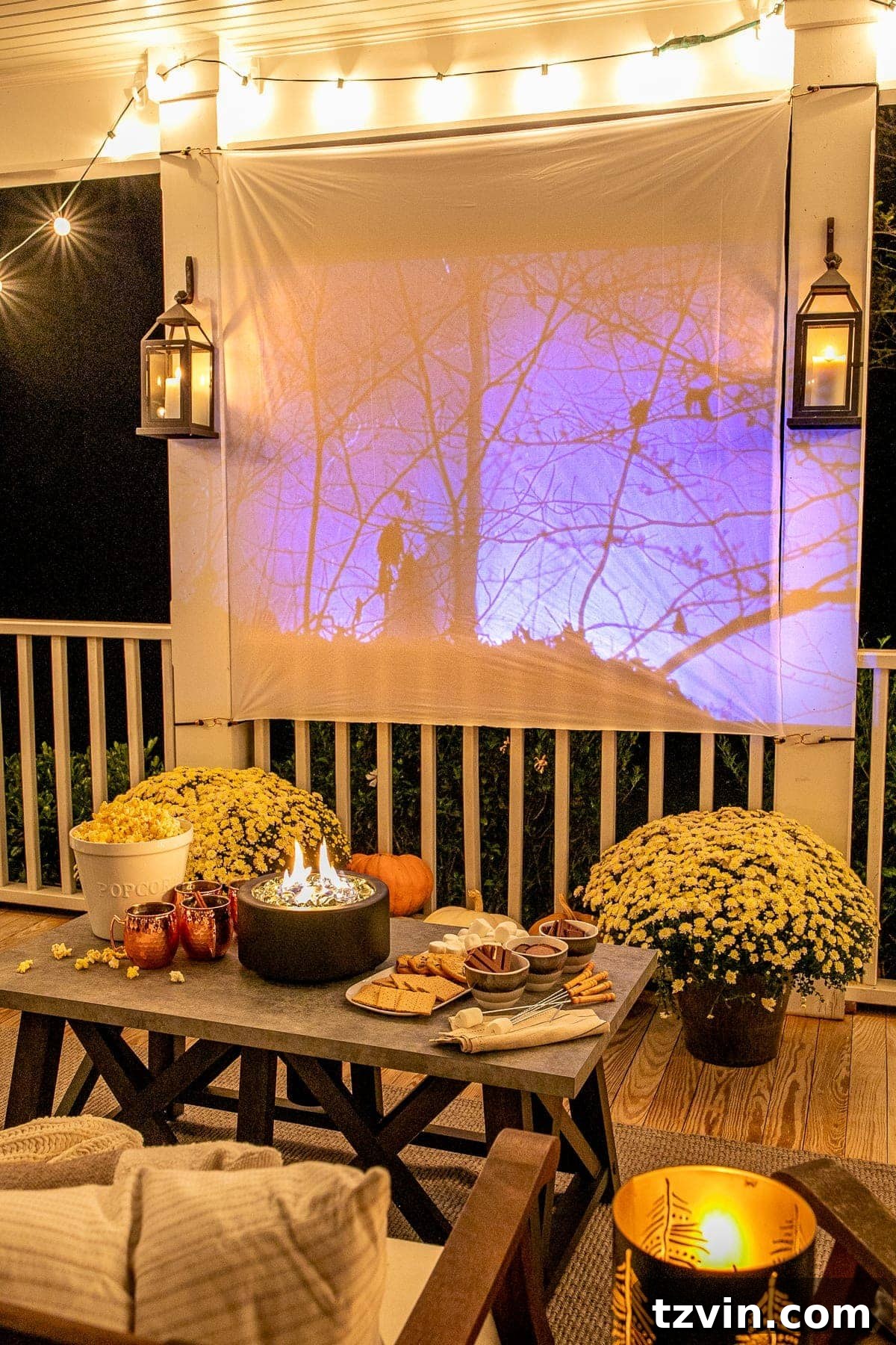 Backyard Blockbuster: Epic Movie Nights Without Breaking the Bank 17 fall movie playing on an outdoor movie screen on a back porch decorated for fall with pumpkins, mums, and tabletop fire pit