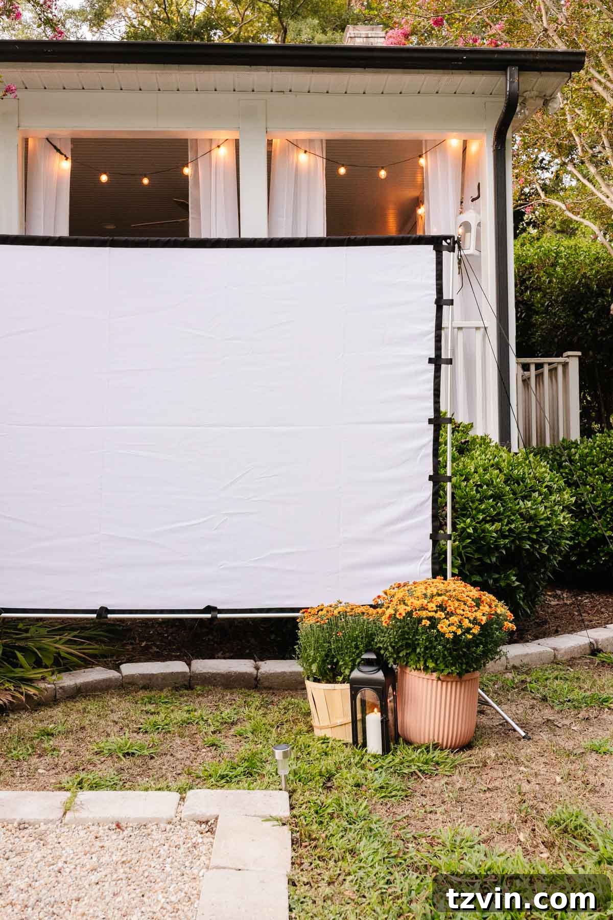Ignite Autumn Nights: 8 Fire Pit Decor Ideas for Your Backyard 11 Outdoor fall decor featuring garden mums and lanterns around an outdoor movie screen for a backyard party