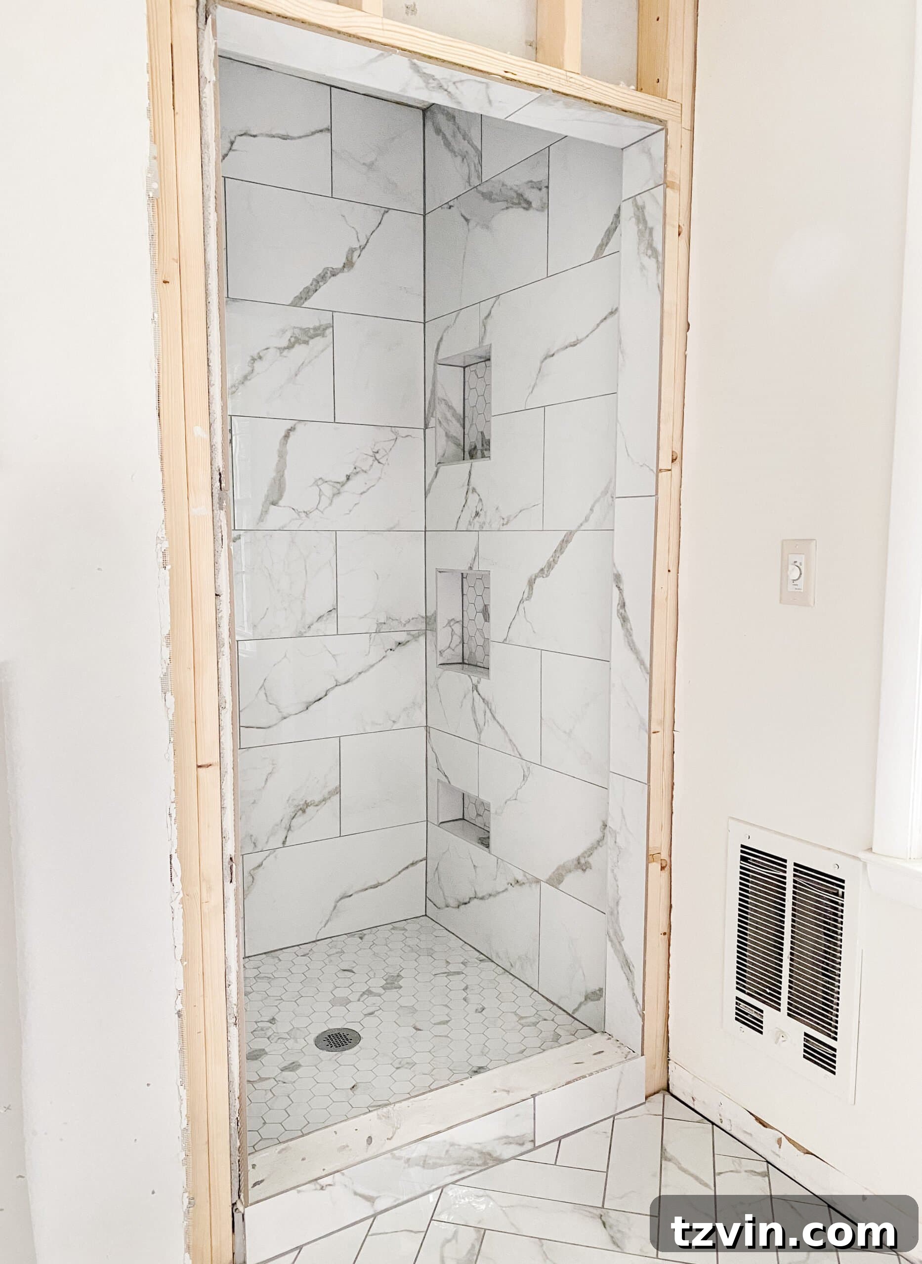 Our Faux Marble Herringbone Shower Transformation 9 faux marble herringbone tile floor flowing into shower with hexagon floor and gray grout