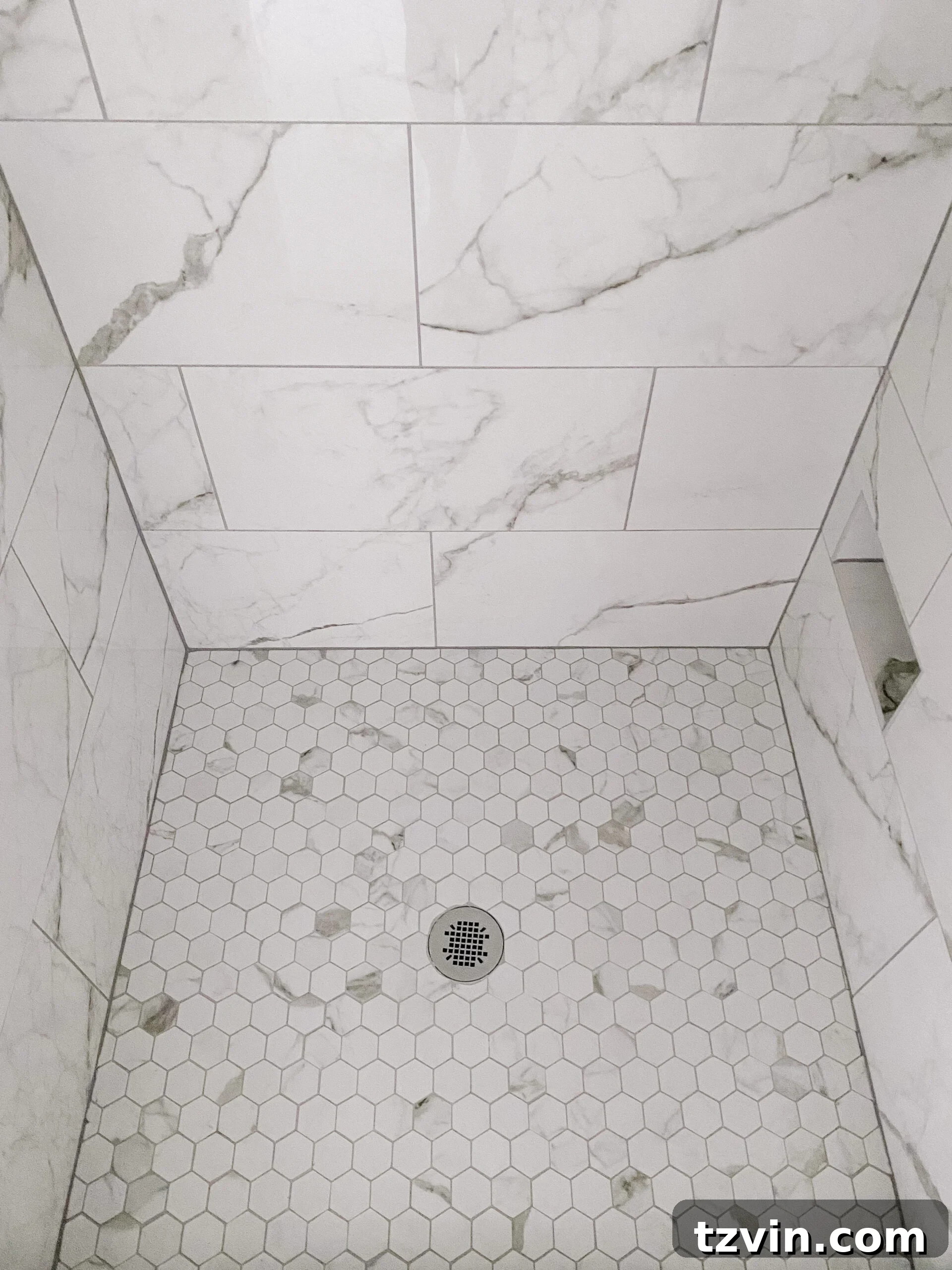 Our Faux Marble Herringbone Shower Transformation 10 detailed view of faux marble hexagon tile shower floor with gray grout