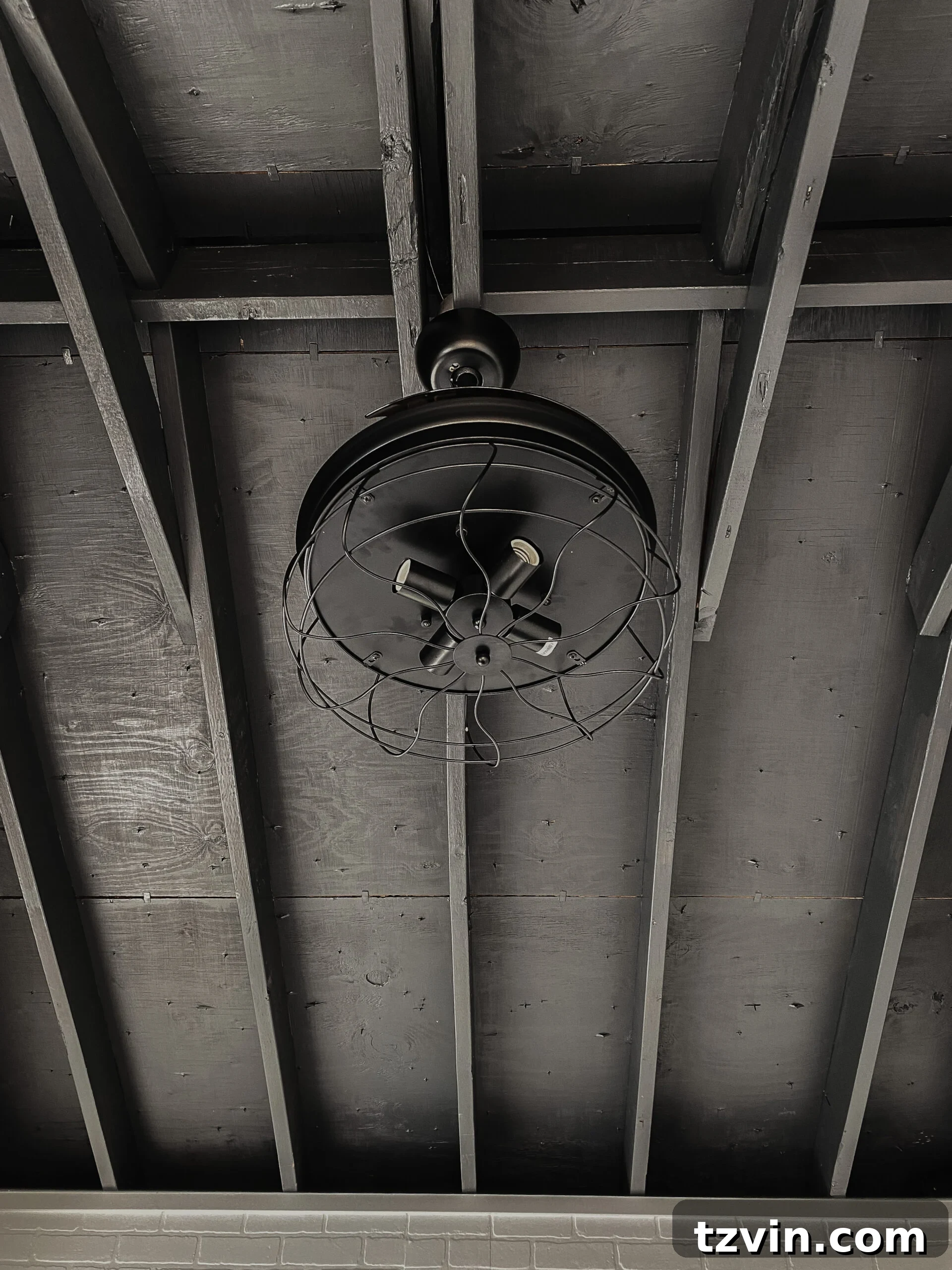 Faux Brick Gym Shed Upgrade 18 A black ceiling fan with retractable blades in an industrial-style home gym, offering both cooling and a sleek design.