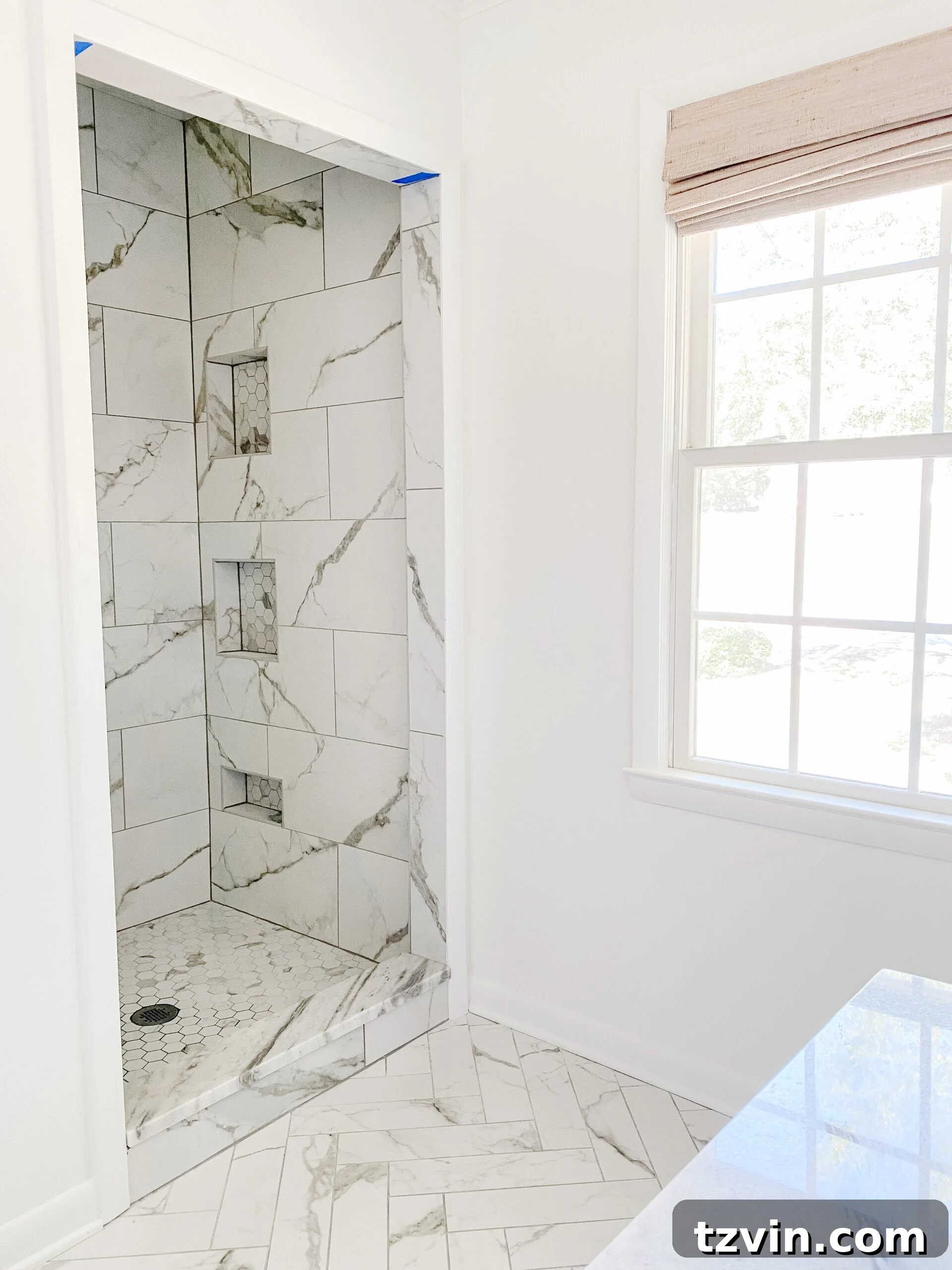 En Suite Bathroom Renovation: Faucets Are Finally Here! 7 A beautifully tiled shower area featuring marble-look porcelain tiles and built-in shower niches, awaiting final fixtures.