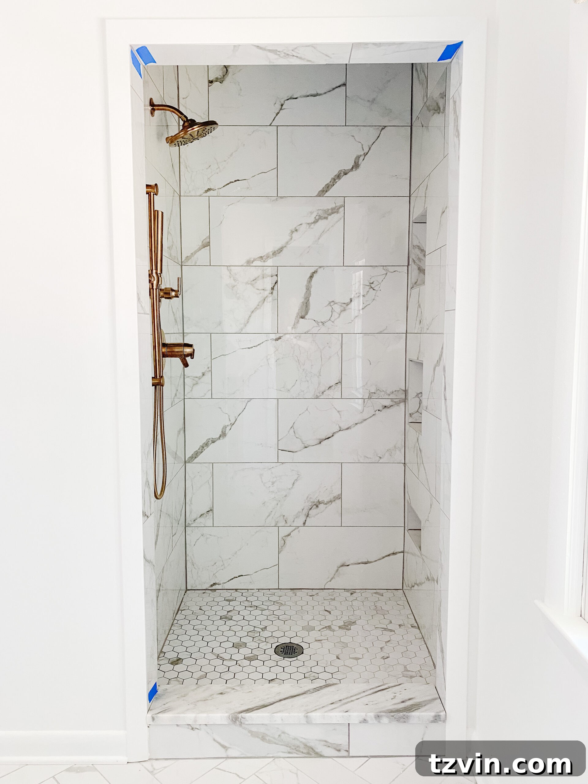En Suite Bathroom Renovation: Faucets Are Finally Here! 8 A stunning faux marble porcelain tile shower with elegant gold shower faucets installed, enhancing the modern classic design.