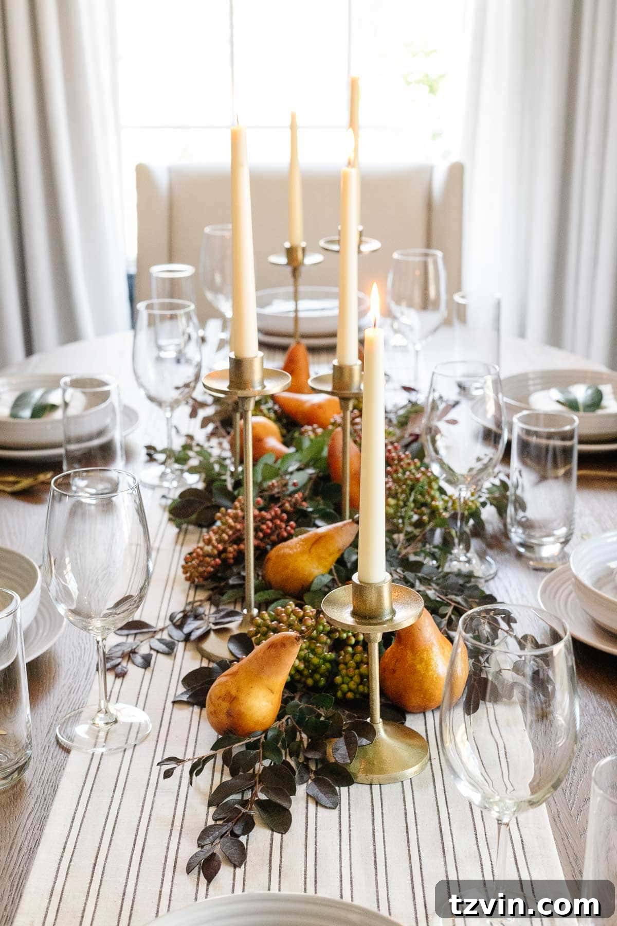 10-Minute Thanksgiving Table Makeover 8 Elegant Thanksgiving centerpiece featuring fresh cut leaves, pears, and lit taper candles, creating a warm and inviting atmosphere.