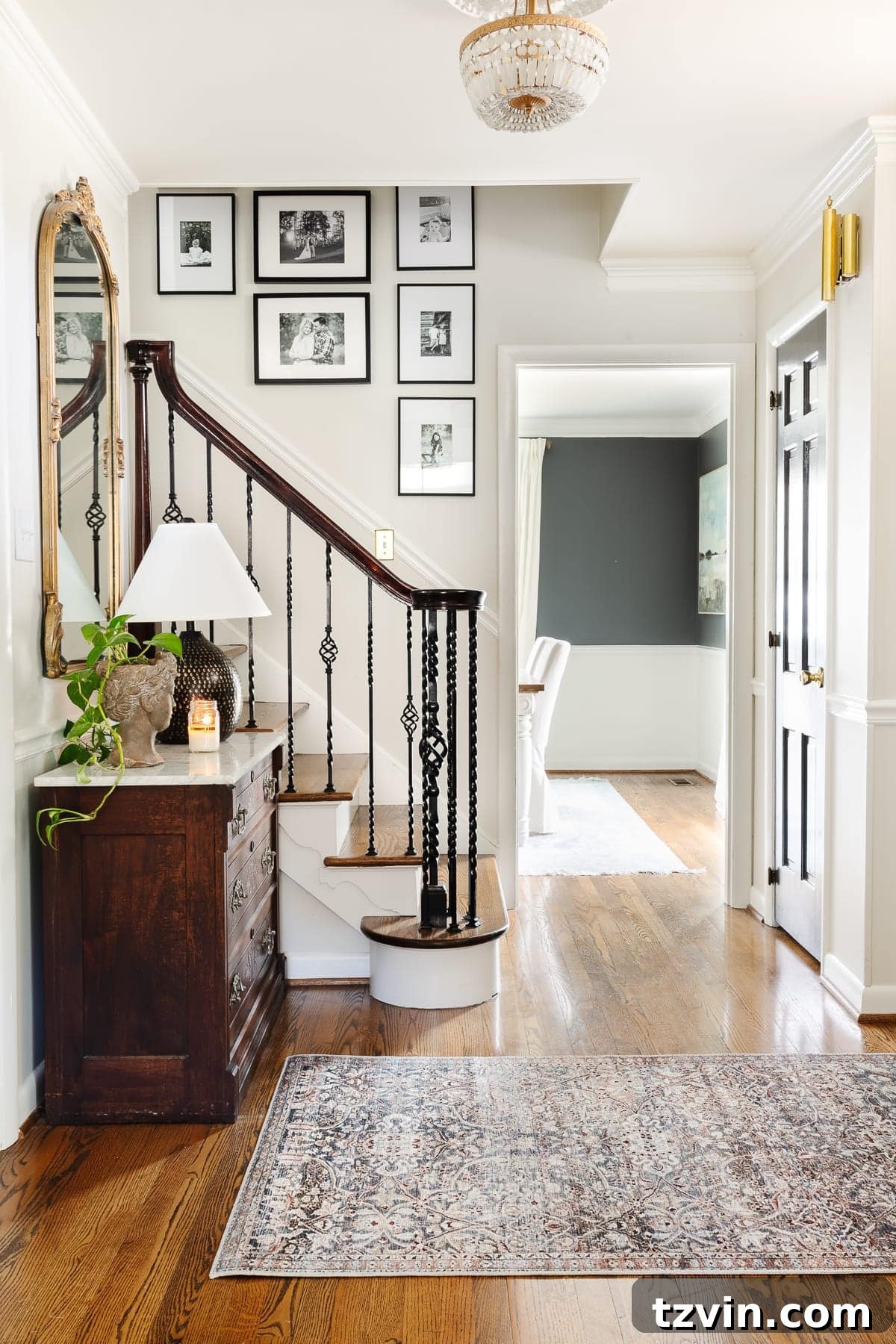 Foyer Fusion Classic Meets Contemporary 3 Entryway featuring an elegant console table, a patterned area rug, and a cohesive stairway gallery display