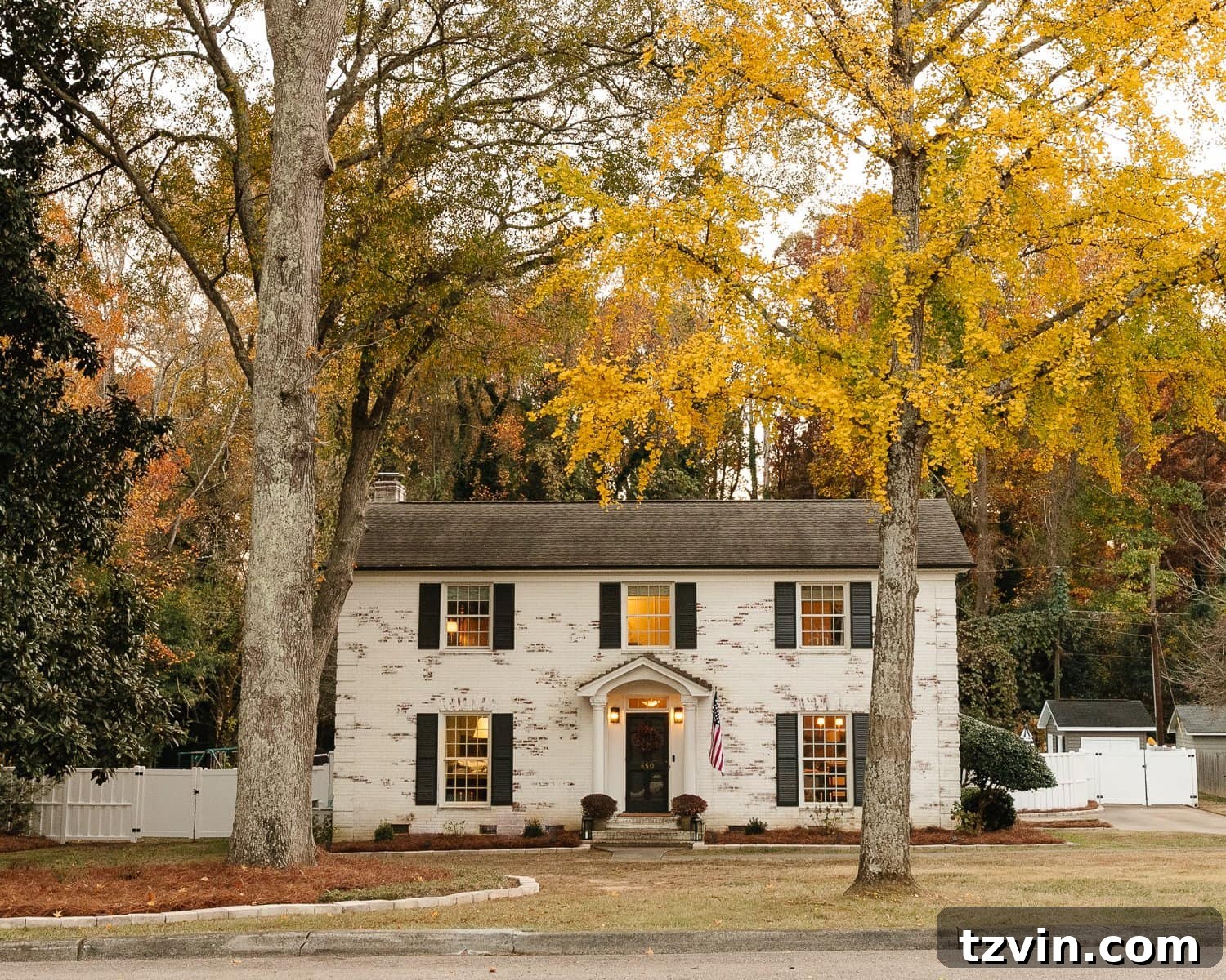 limewashed brick colonial house with fall trees 