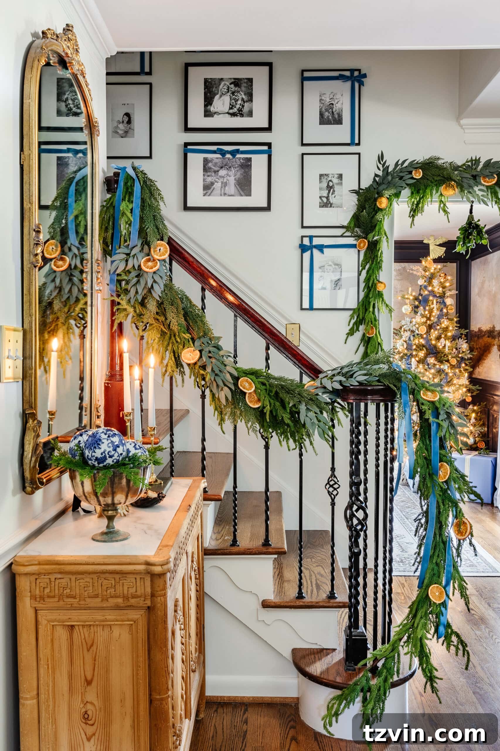 Craft Your Own Beautiful Dried Orange Garland 14 Dried orange slices intertwined with lush garland greenery on a staircase railing, enhancing Christmas home decor.