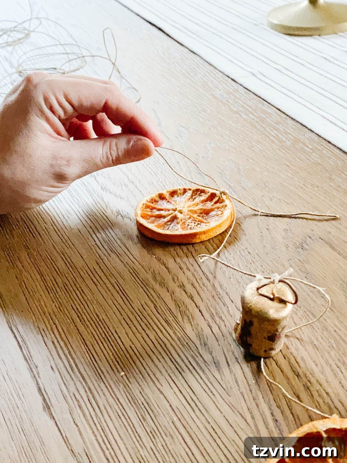 Craft Your Own Beautiful Dried Orange Garland 6 A dried orange slice with a short length of twine threaded through it, ready to be tied.