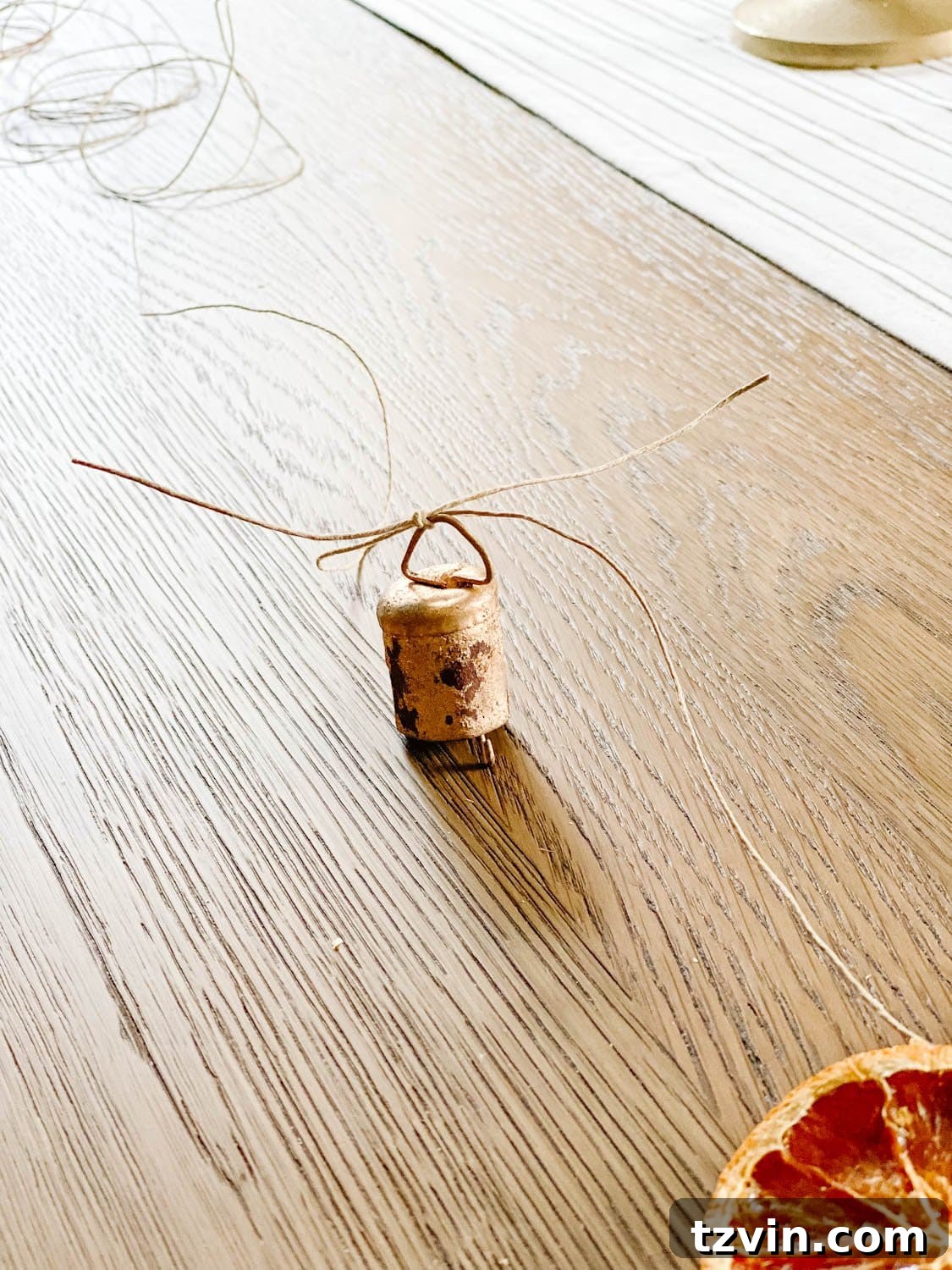 Craft Your Own Beautiful Dried Orange Garland 10 Close-up of a mini brass bell securely tied with twine onto the garland.