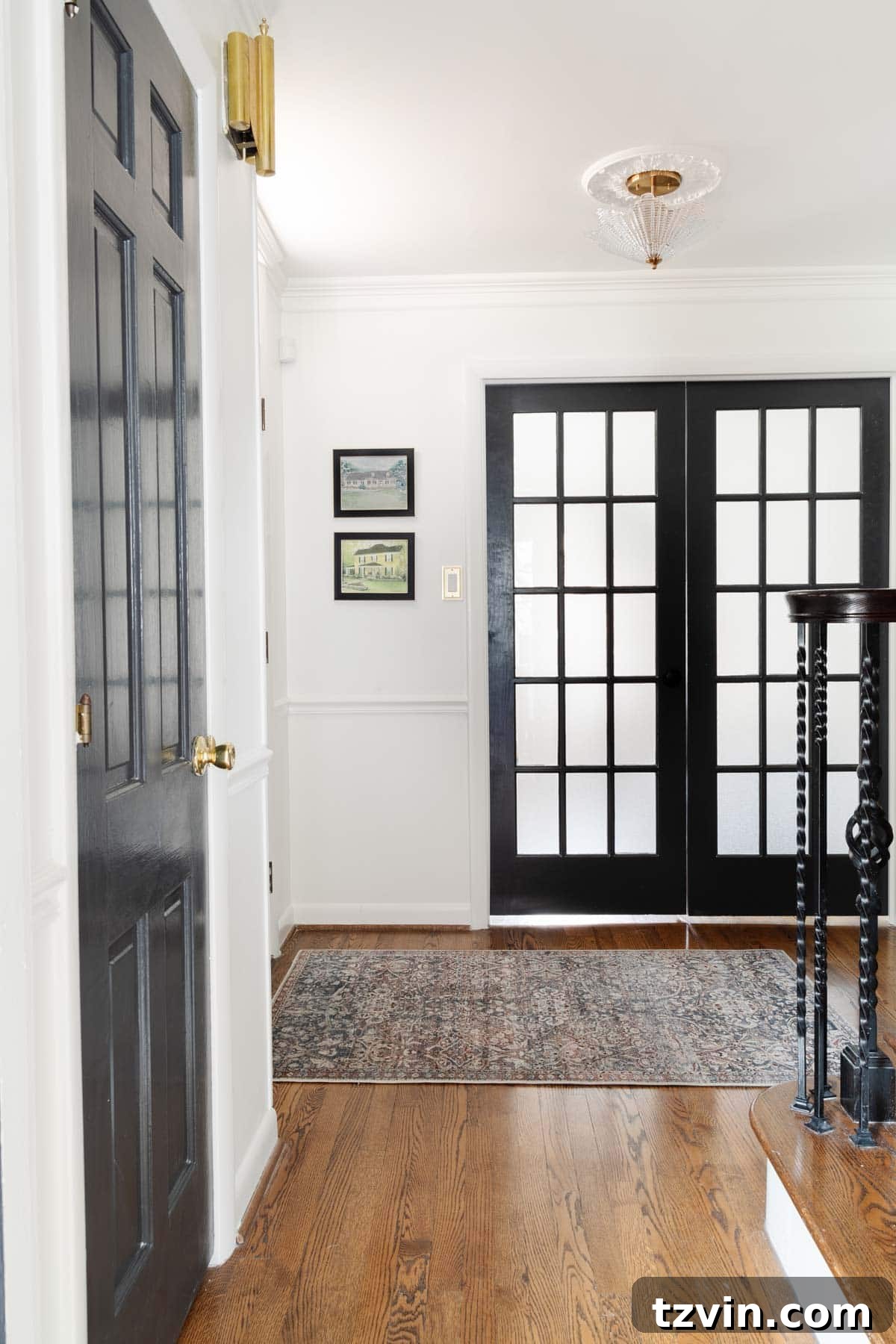 A stylish foyer featuring a vintage-style rug and black doors, demonstrating an affordable entryway decor solution.