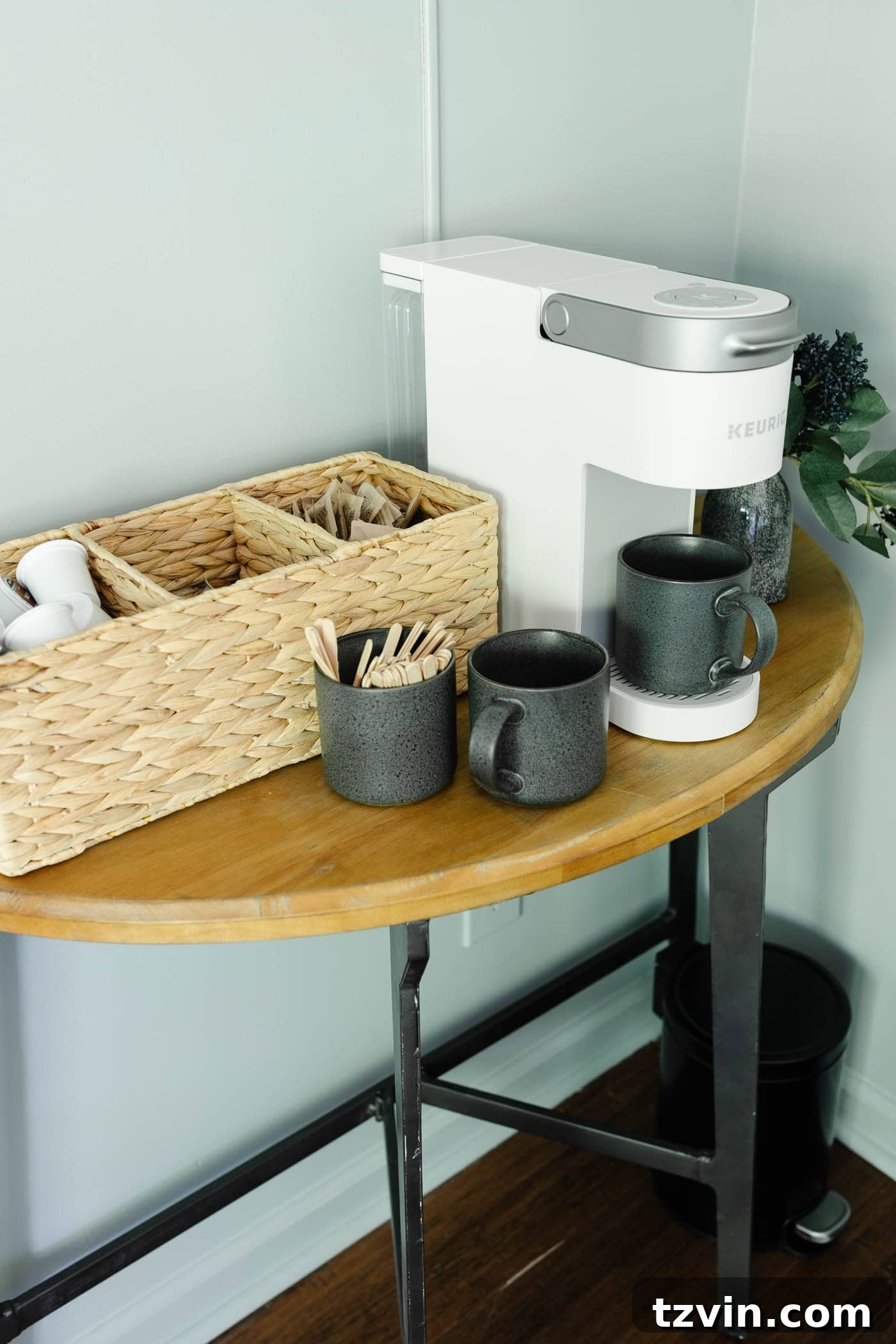 A close-up of a well-organized coffee bar within an office lounge, with speckled mugs and a divided basket for essentials.
