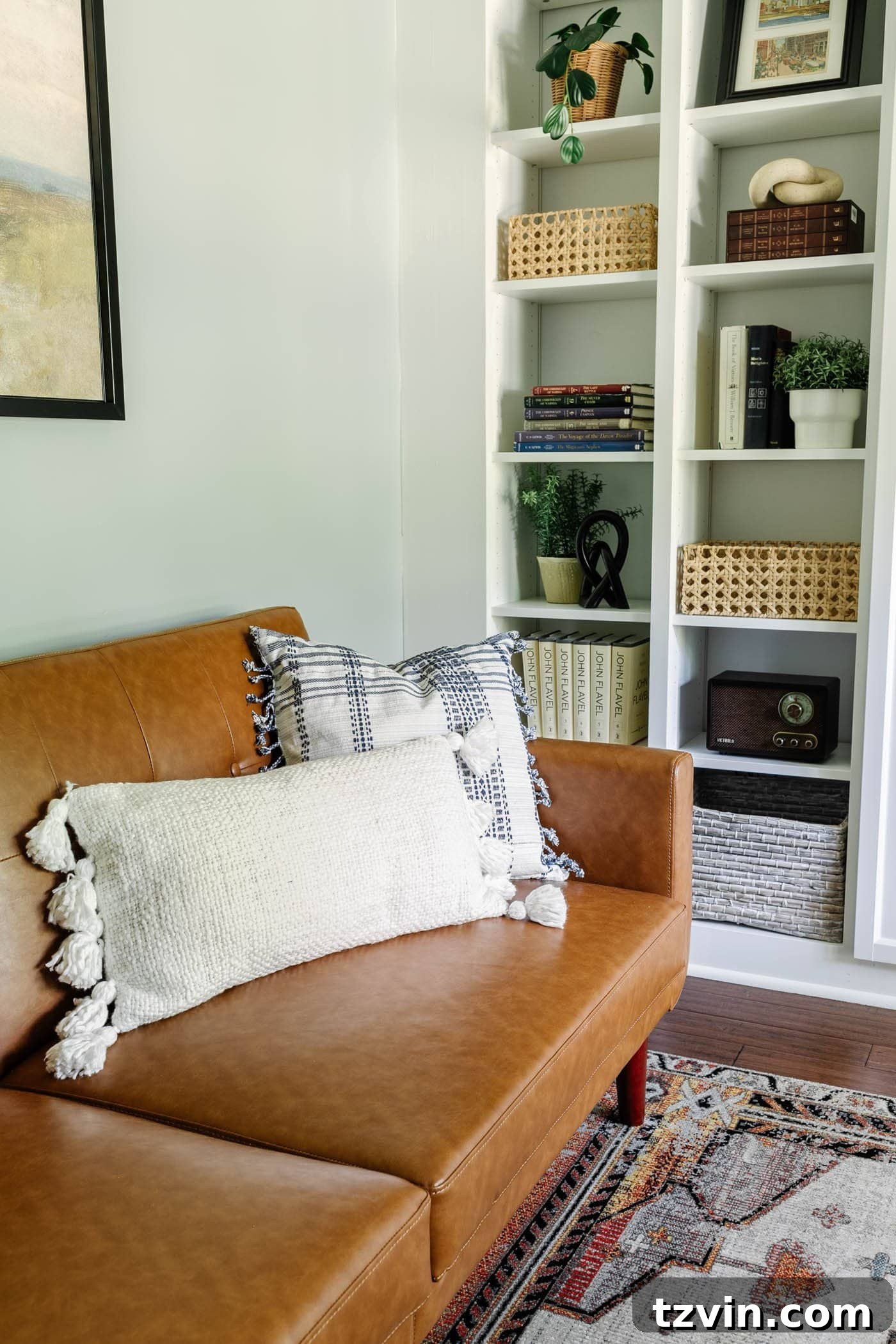 Cozy reading nook with a Walmart faux leather futon, complemented by functional IKEA built-in office shelving, creating a balanced space for work and relaxation.
