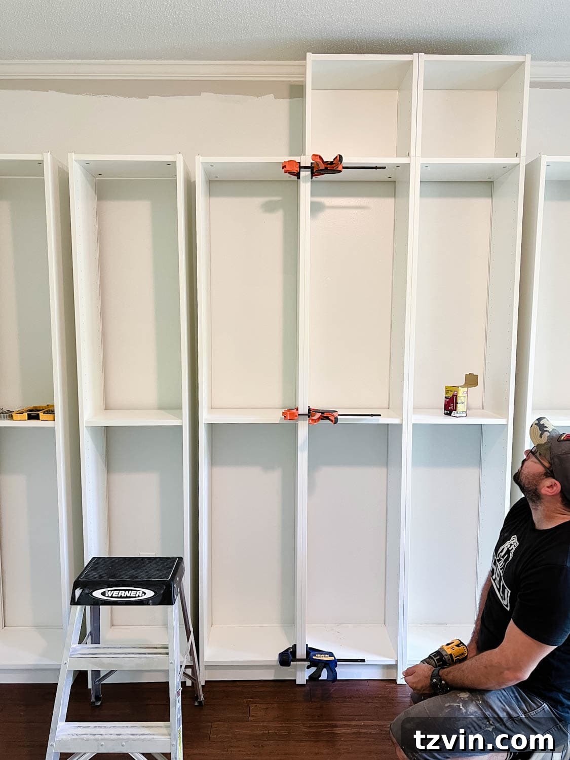Building Custom Bookshelves with IKEA Billy Bookcase Hacks 11 using clamps to keep bookcases together to attach them with wood screws to make diy built in bookshelves