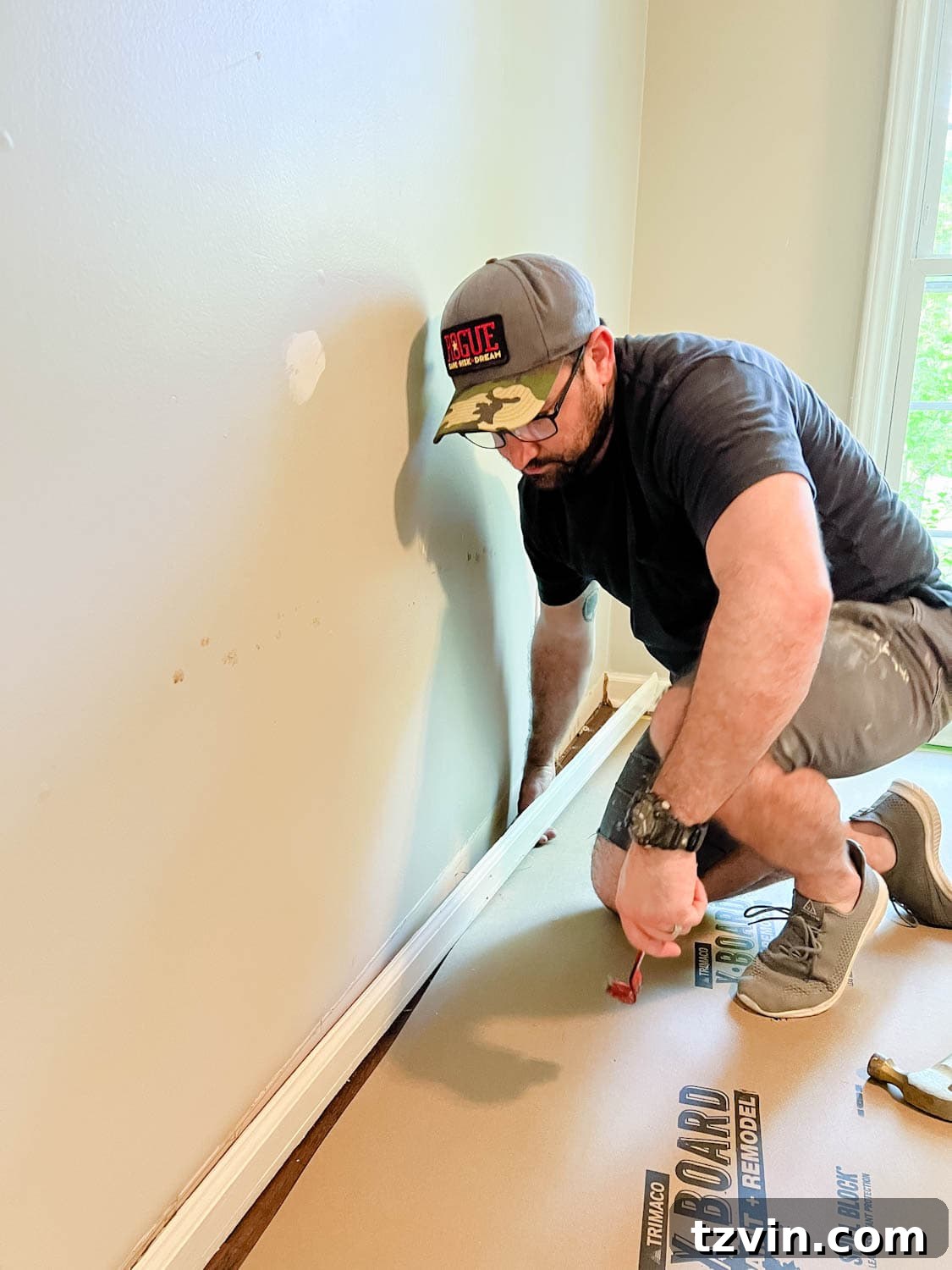 Building Custom Bookshelves with IKEA Billy Bookcase Hacks 4 removing a baseboard from a wall using a pry bar and hammer