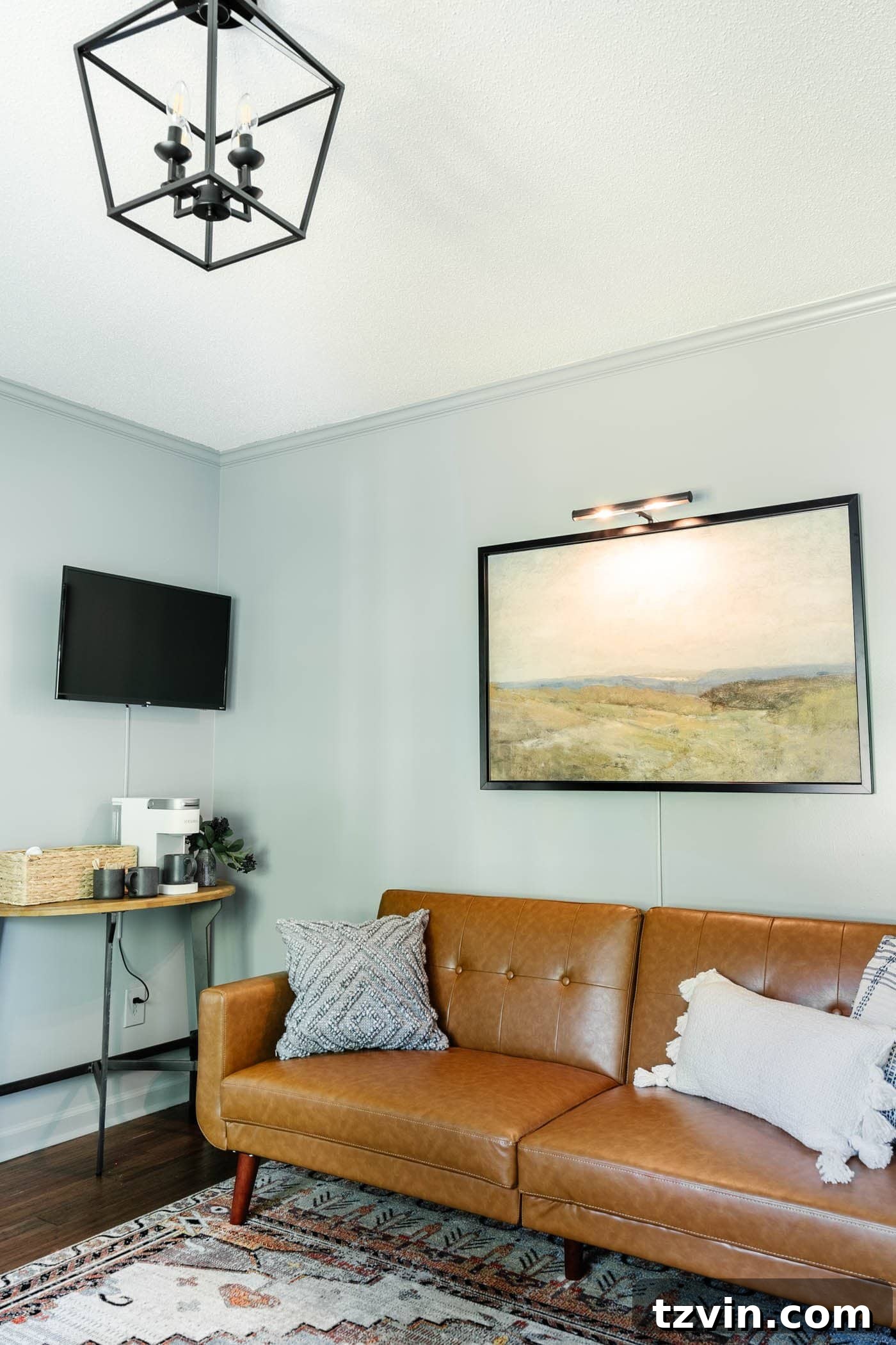 Art with picture light above a home office lounge sofa with coffee bar table and TV area