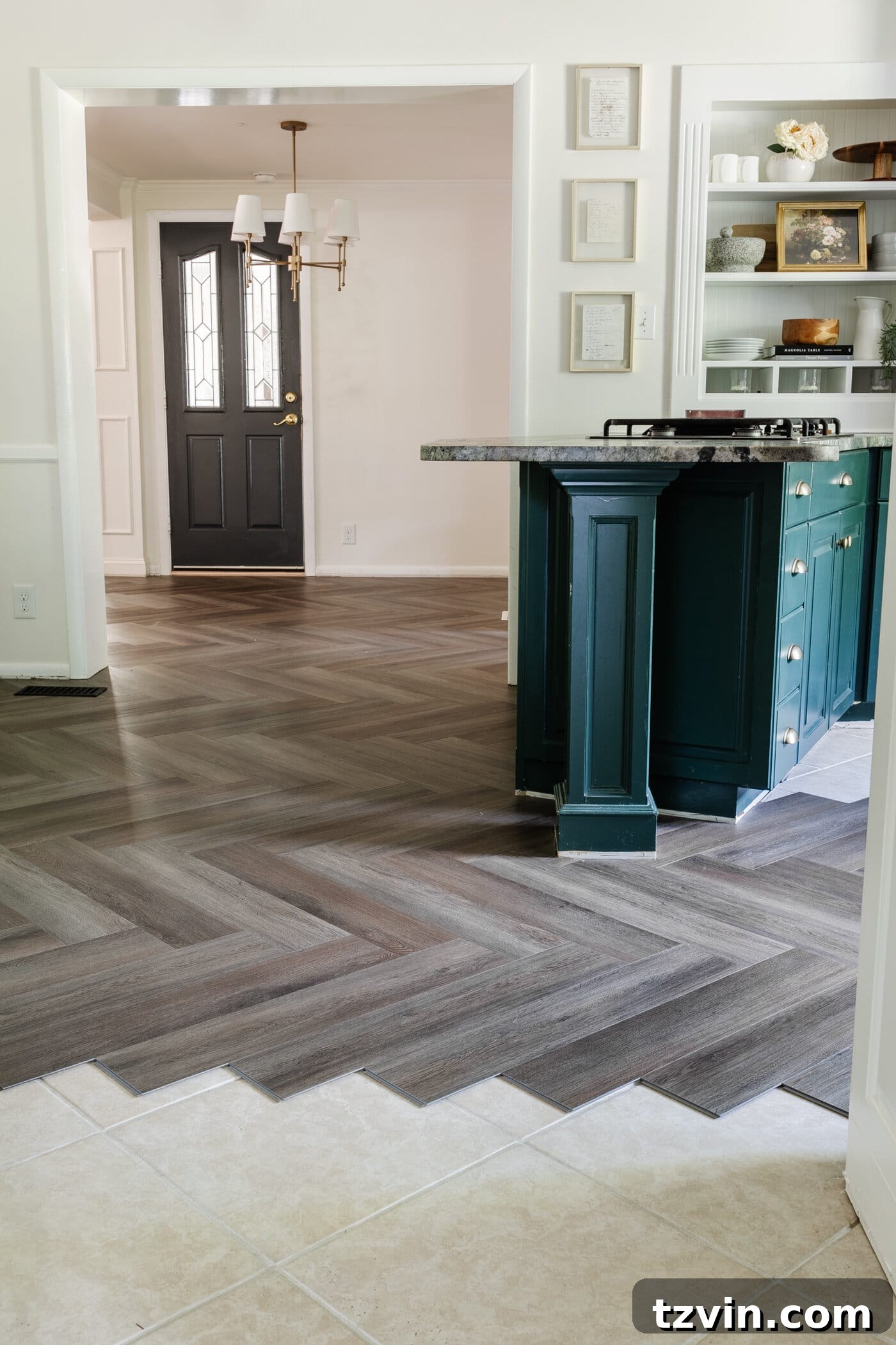 herringbone LVP floating floor over tile in a kitchen with white and green cabinets