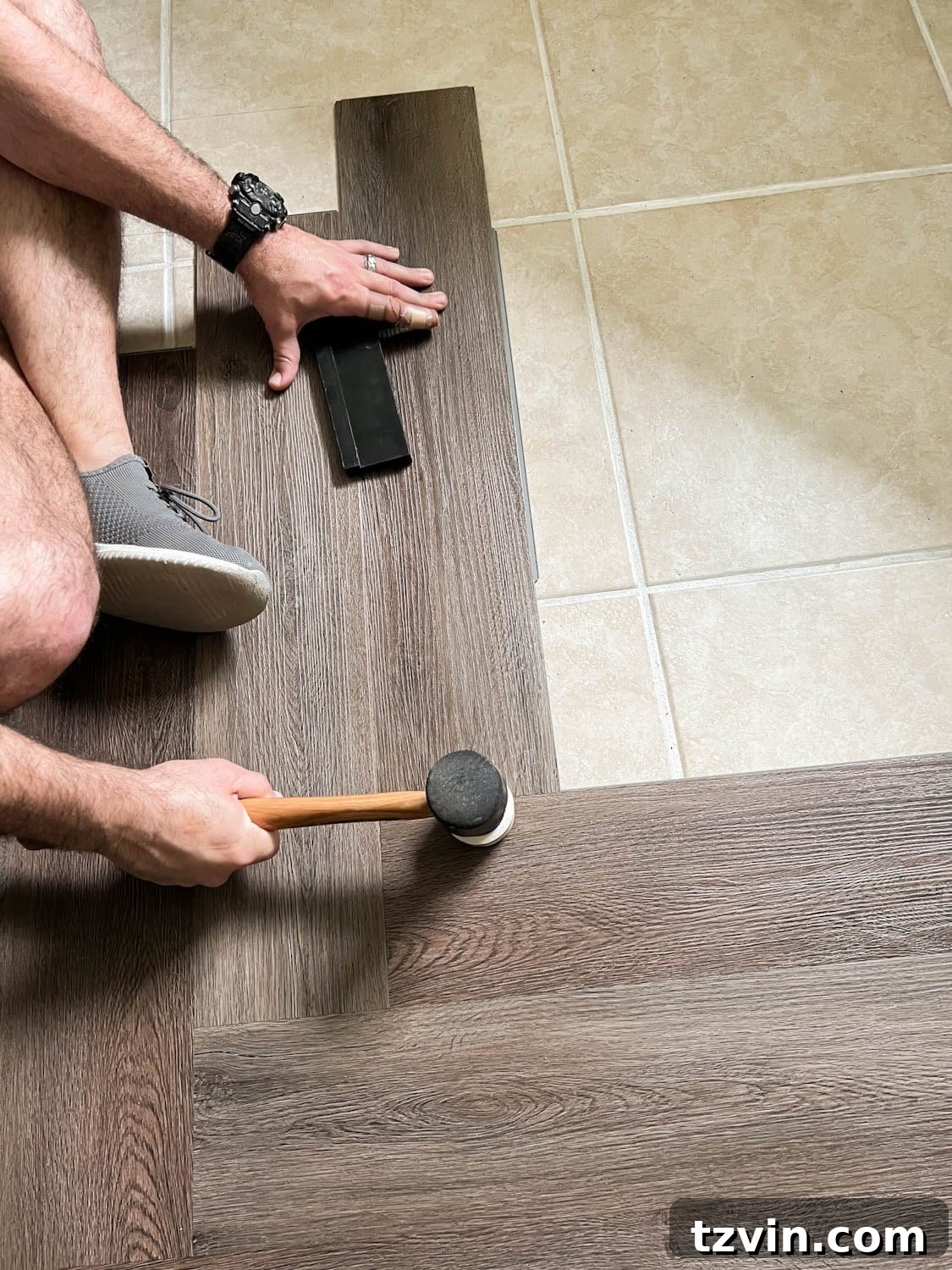 installing herringbone LVP floating floor over tile with mallet on seams to click into place