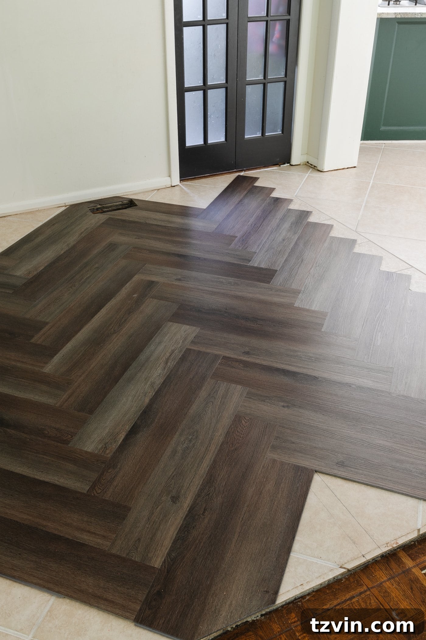 brown herringbone LVP floating floor over tile in a kitchen