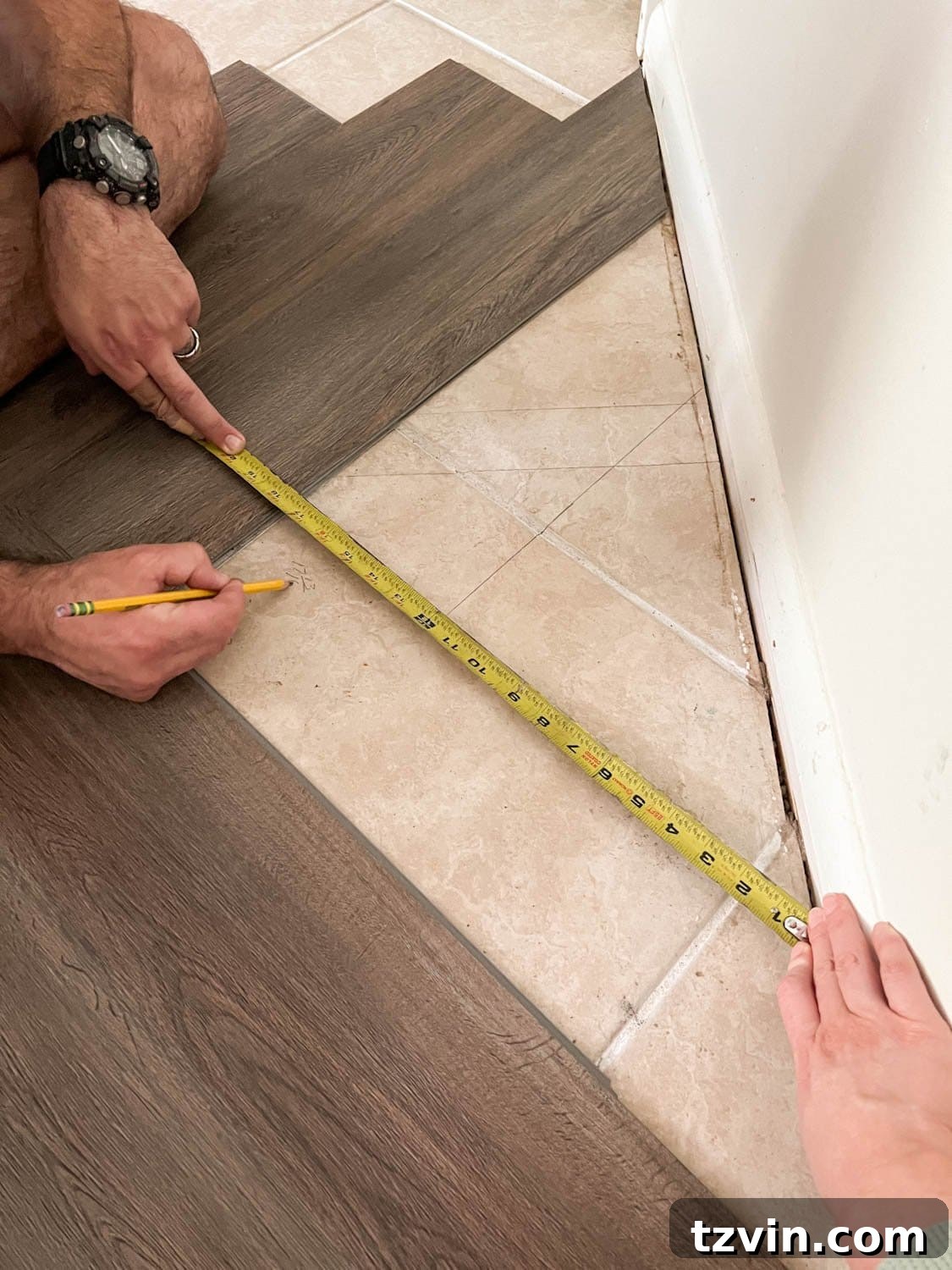 marking measurements to cut flooring pieces to fit against wall