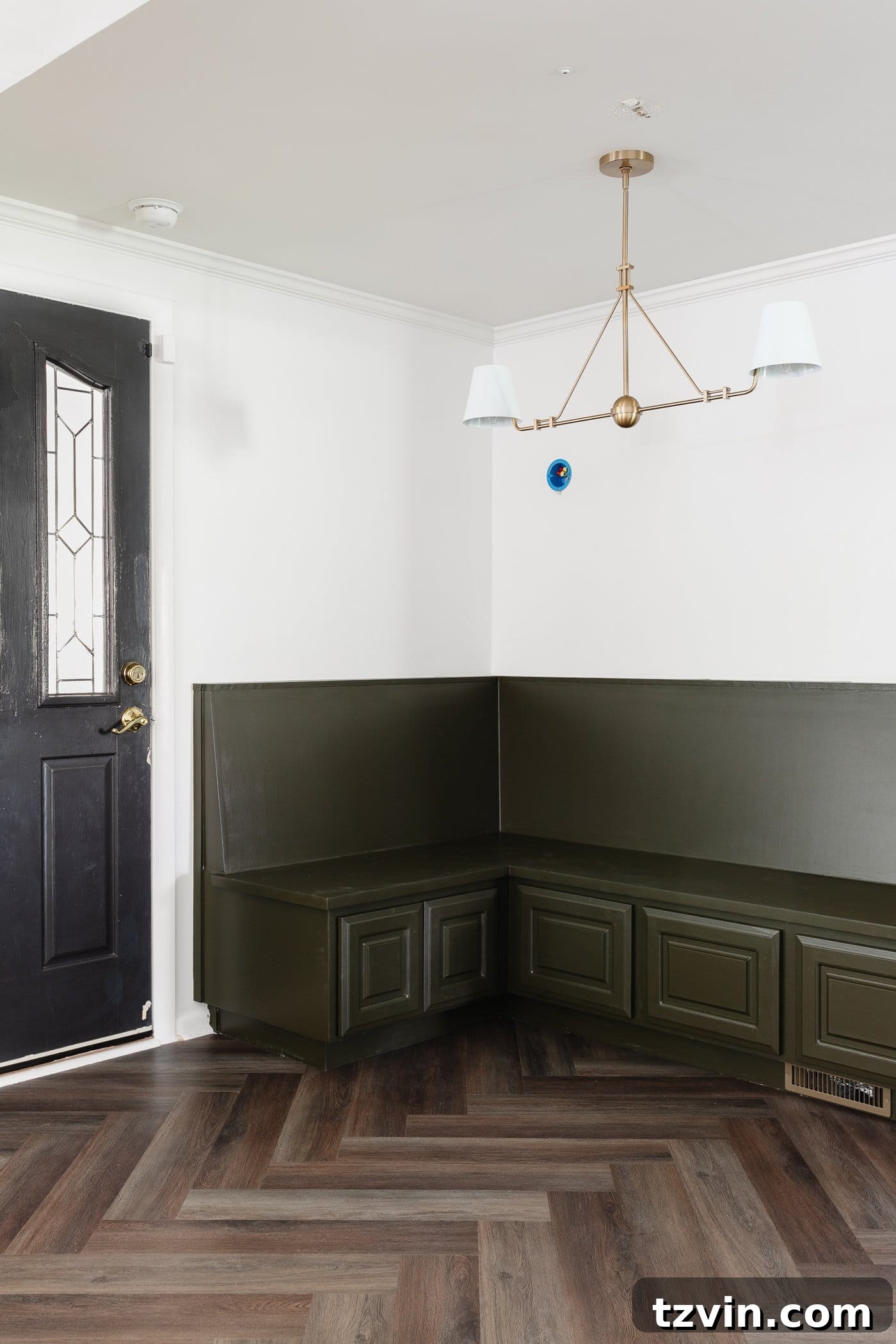 corner banquette in a breakfast nook with linear chandelier and herringbone floor