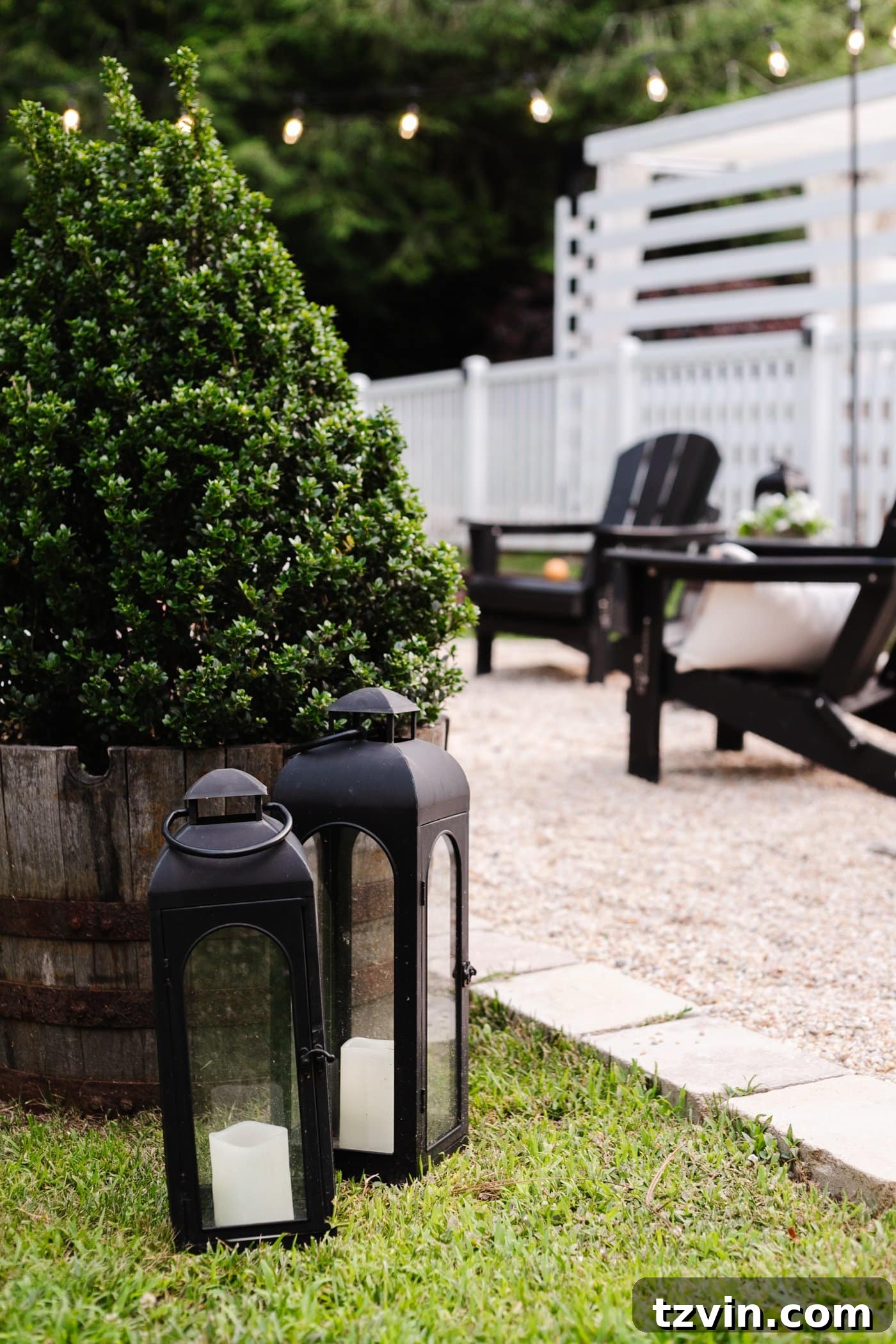 Illuminate Your Nights: Simple DIY Backyard Lighting Projects 13 two elegant black lanterns illuminating a pea gravel backyard fire pit area with surrounding boxwood trees