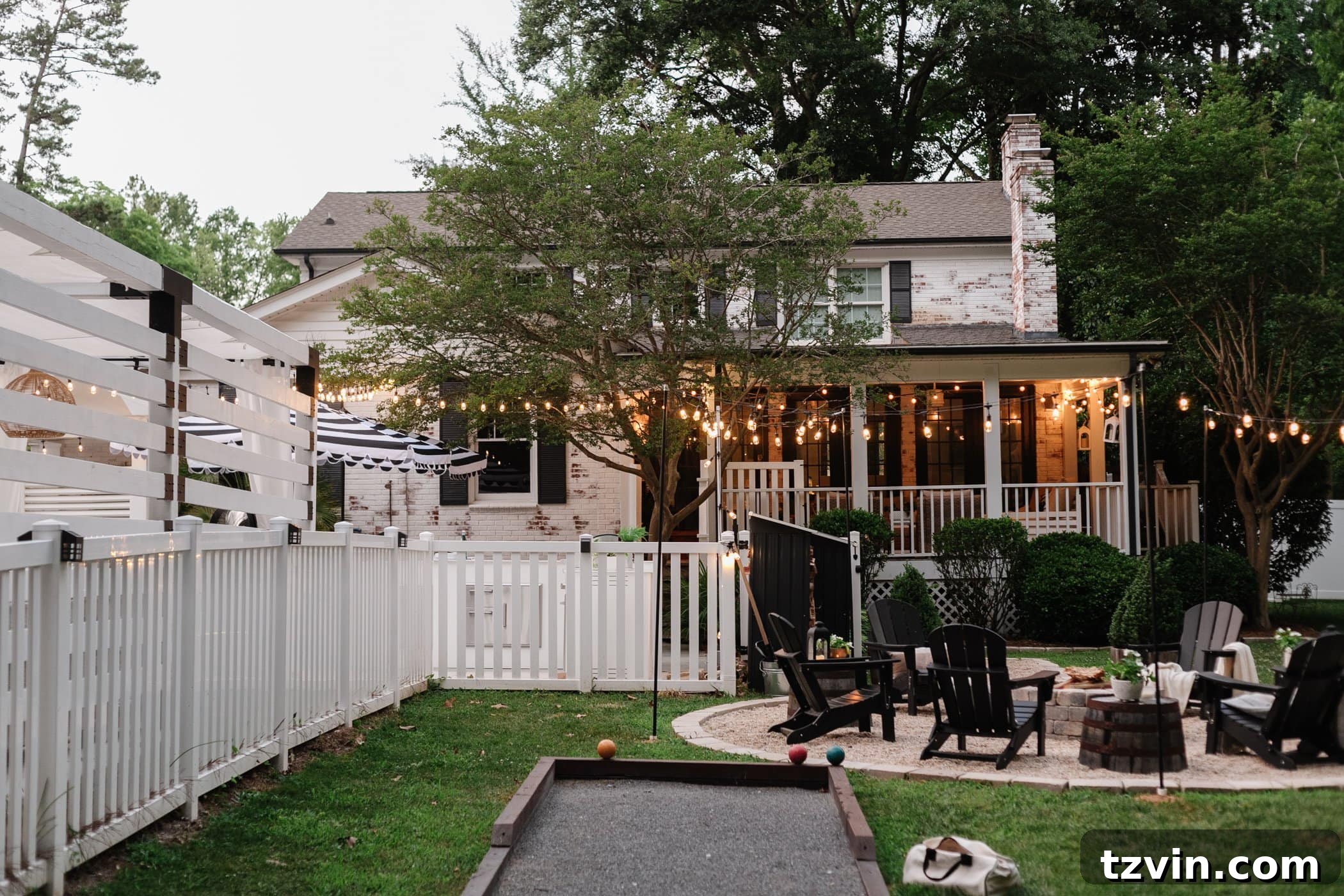 Illuminate Your Nights: Simple DIY Backyard Lighting Projects 16 a serene backyard with string lights, a bocce ball court, and a fire pit surrounded by black Adirondack chairs