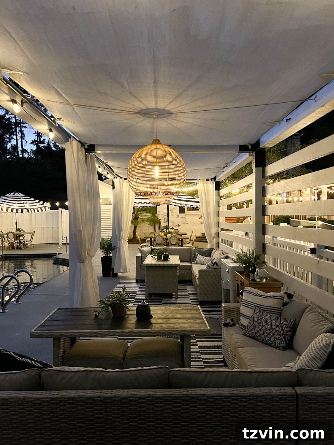 Illuminate Your Nights: Simple DIY Backyard Lighting Projects 7 a beautifully lit pergola cabana with patio dining furniture, solar pendant lights, and string lights beside a sparkling pool at night