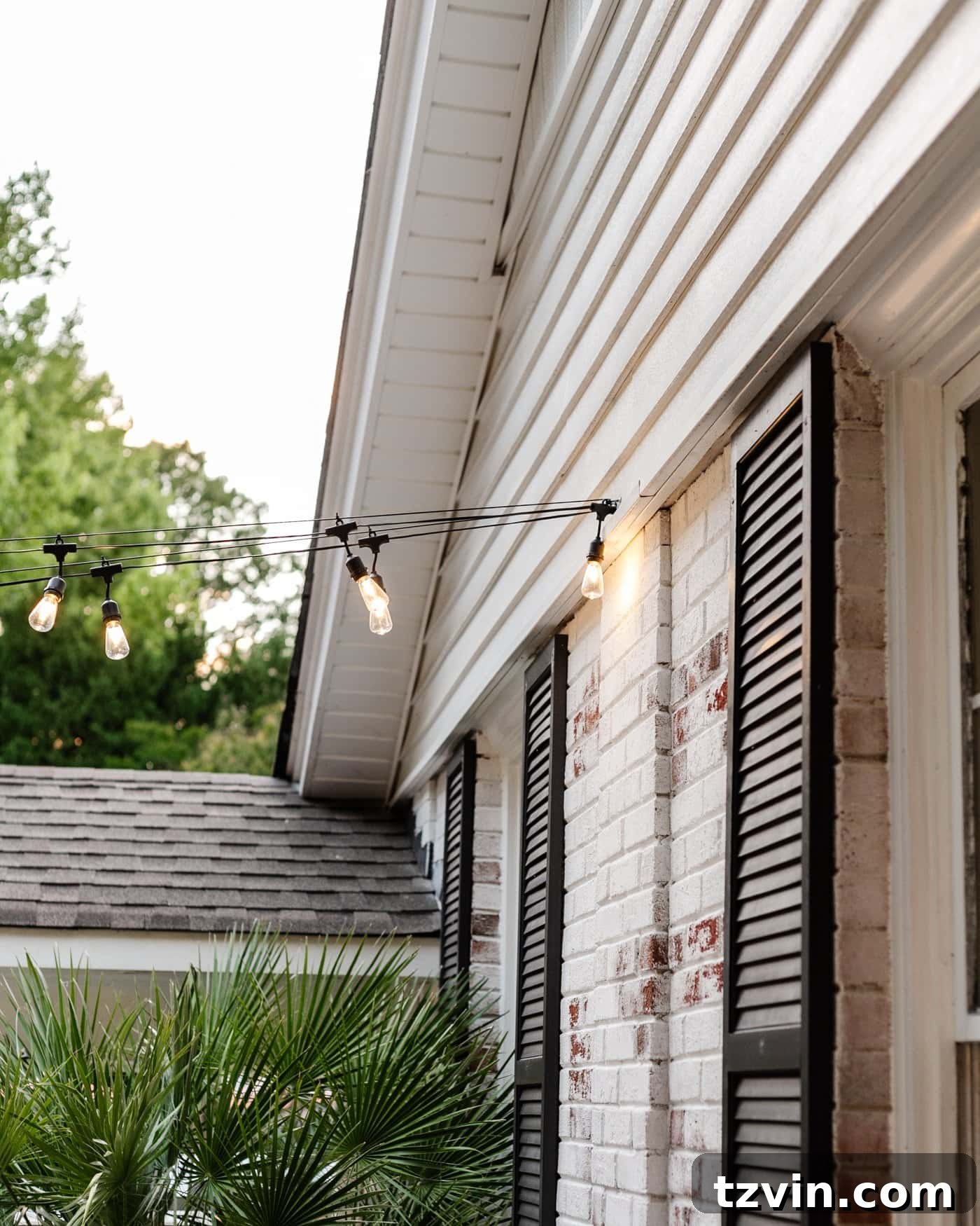 Creative String Light Solutions for Every Backyard Corner 4 string lights hanging from a hook on the side of a brick house