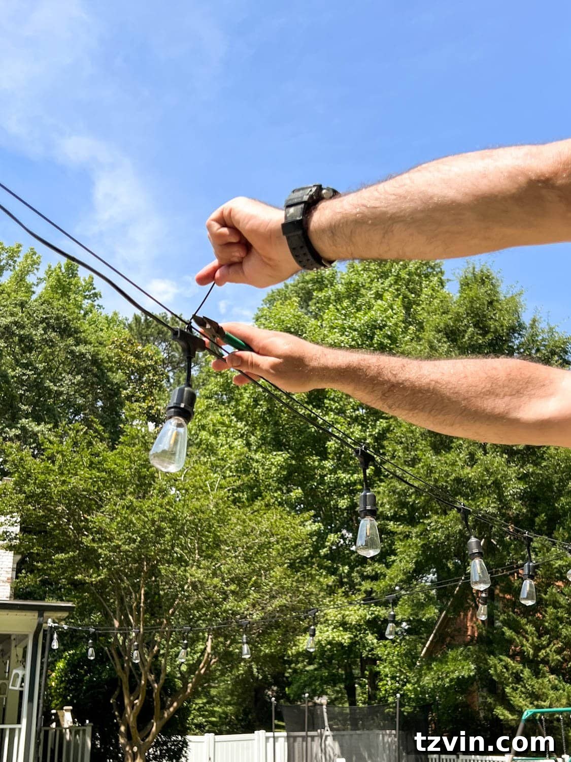 Creative String Light Solutions for Every Backyard Corner 44 snipping zip tie ends to attach string lights to cable