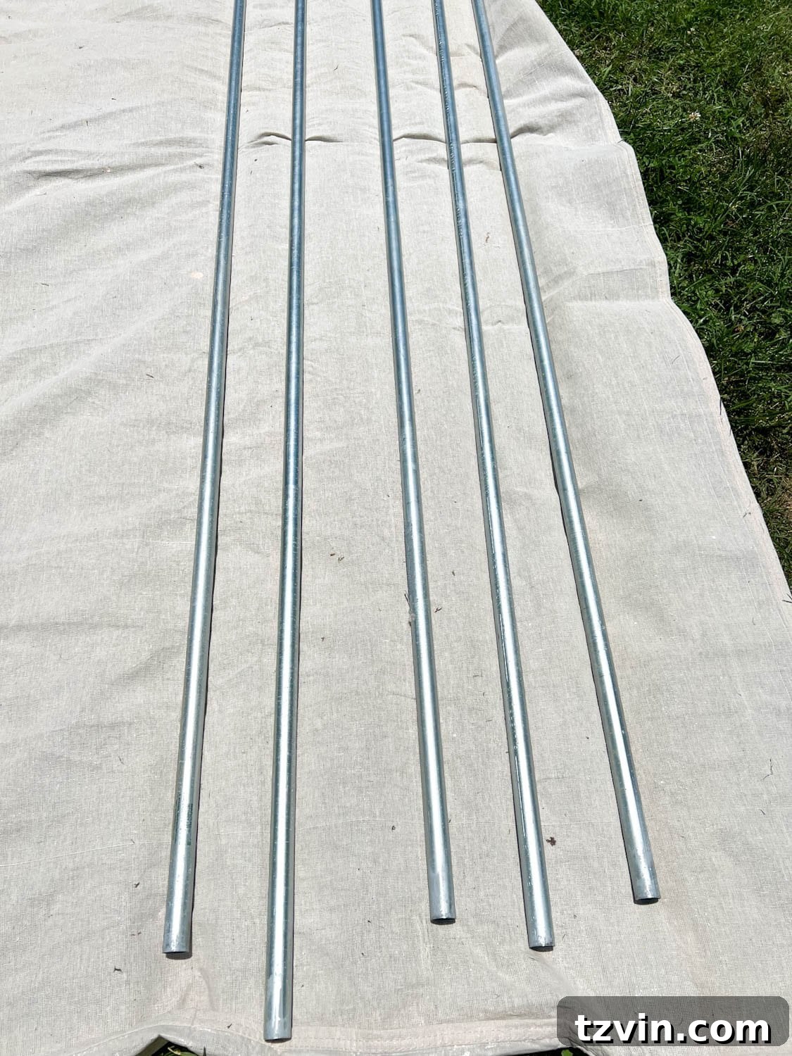 Creative String Light Solutions for Every Backyard Corner 10 conduit poles on a drop cloth ready to be painted