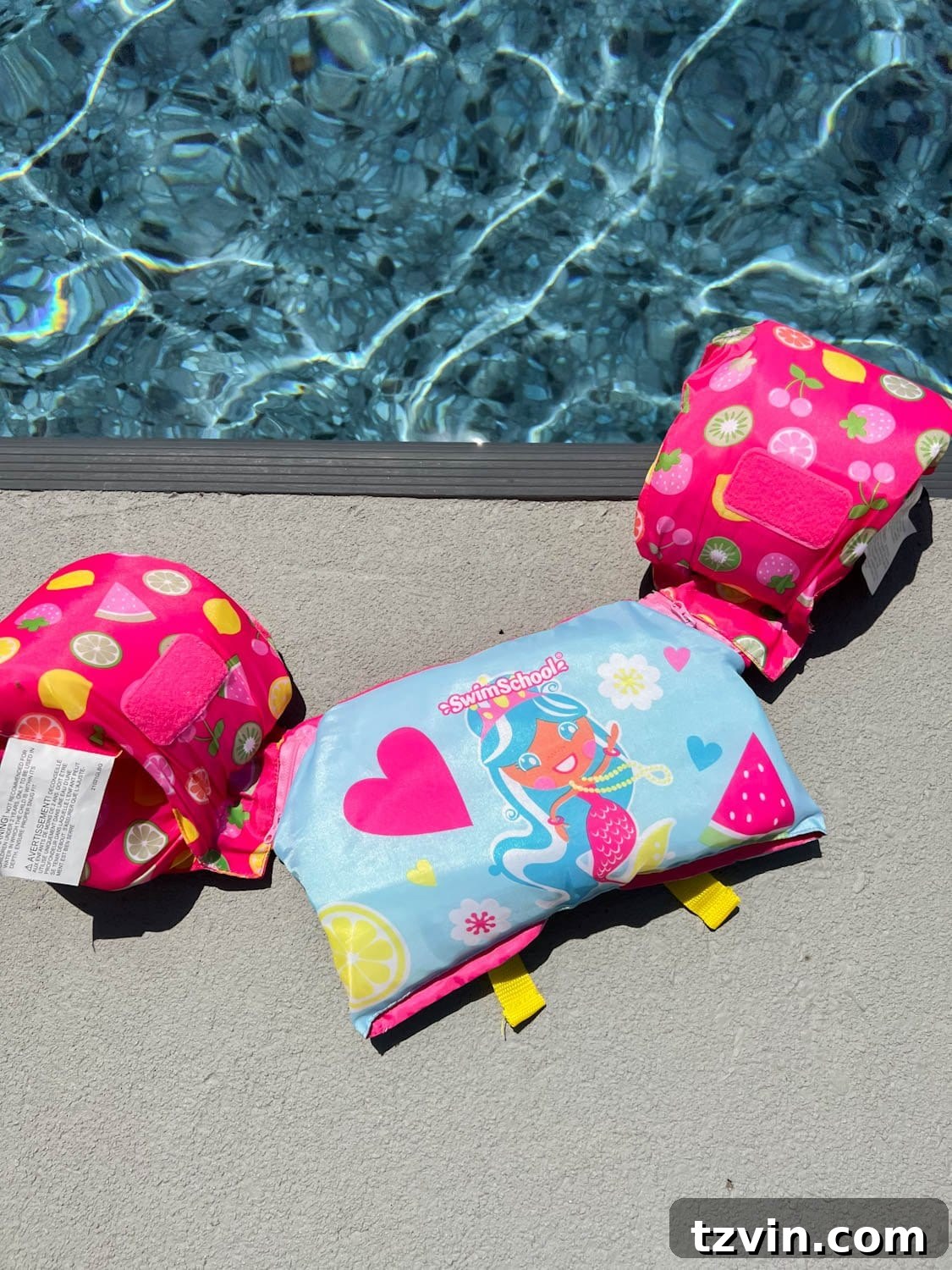 toddler swim vest on the ground on the side of a swimming pool