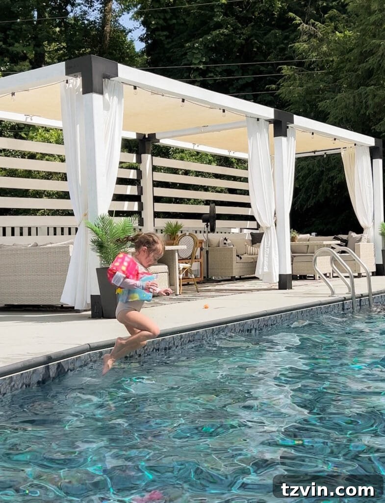 toddler girl jumping into a backyard swimming pool with a vest