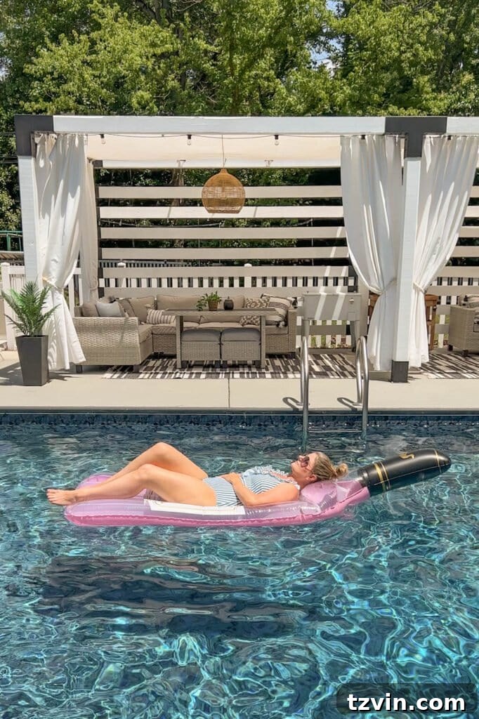 woman lying on a wine bottle shaped pool flat in the water in front of a cabana