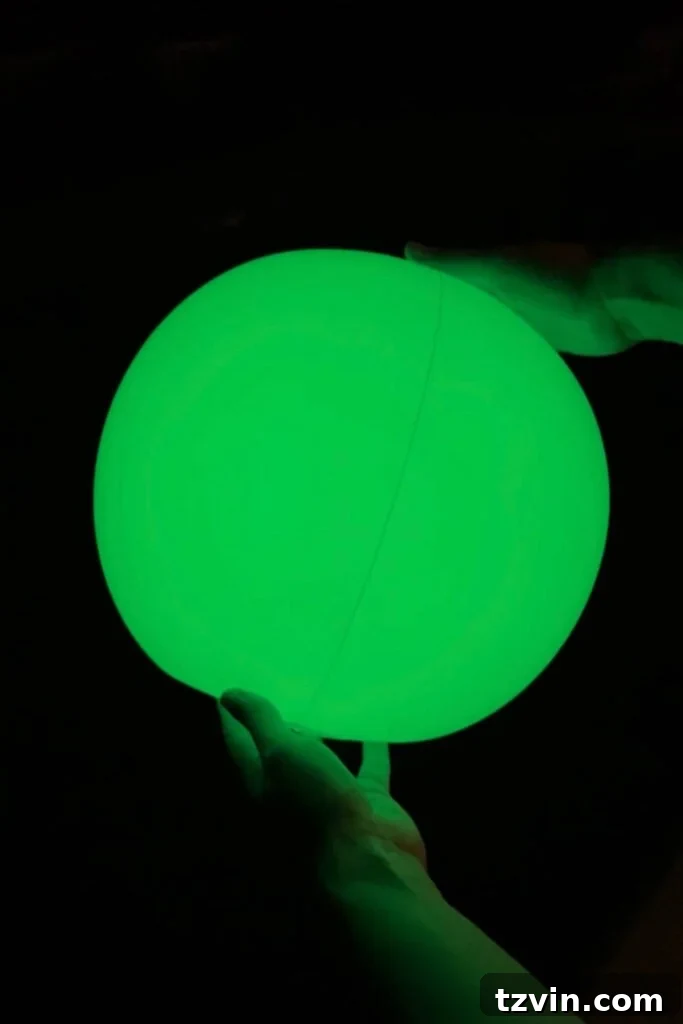 light up beach ball glowing green at night