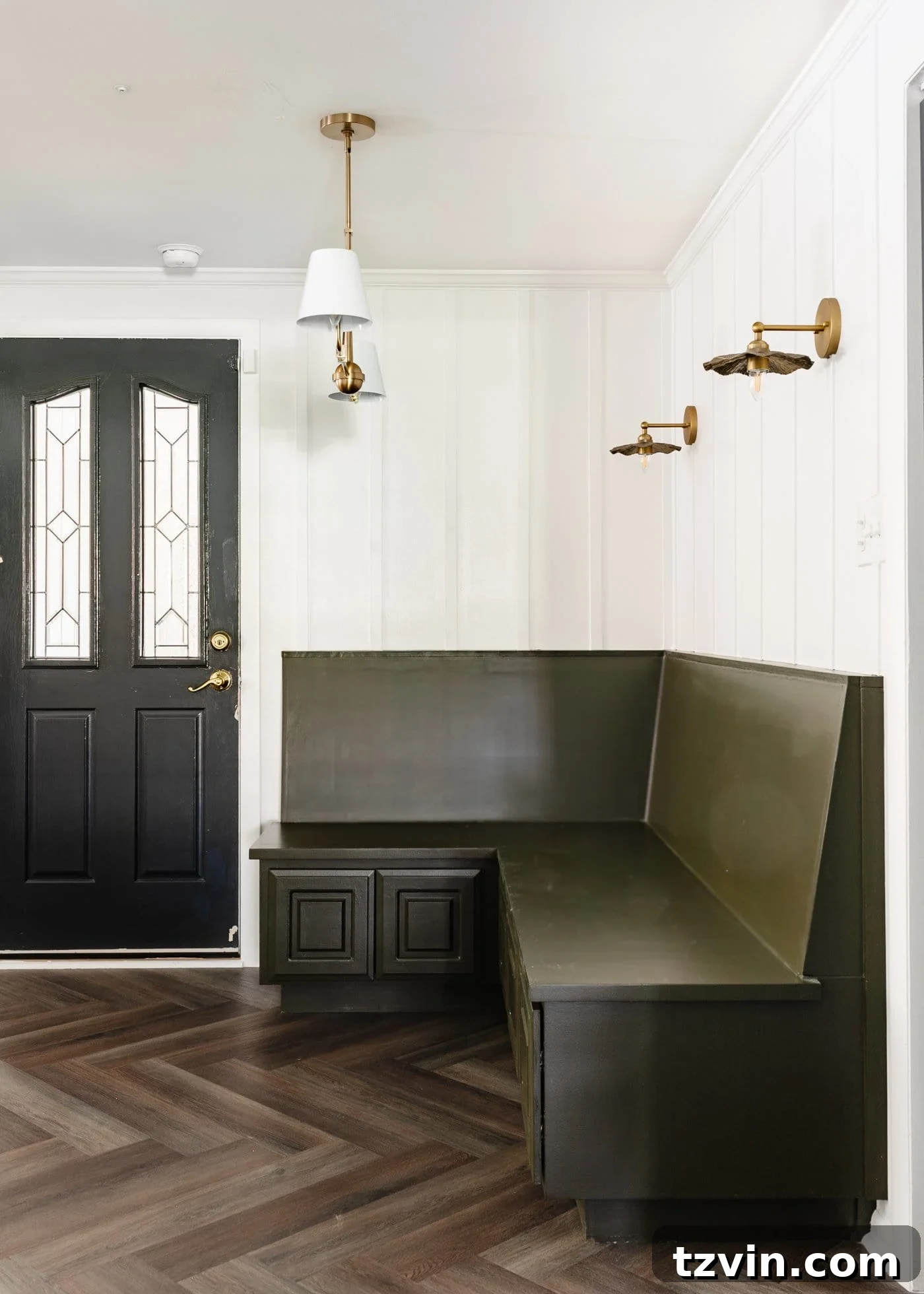 Create a Budget Batten Wall with Lattice Strips 13 An inviting olive green banquette bench nestled in a breakfast nook, complemented by white batten walls, herringbone LVP floors, and a striking black bifold door