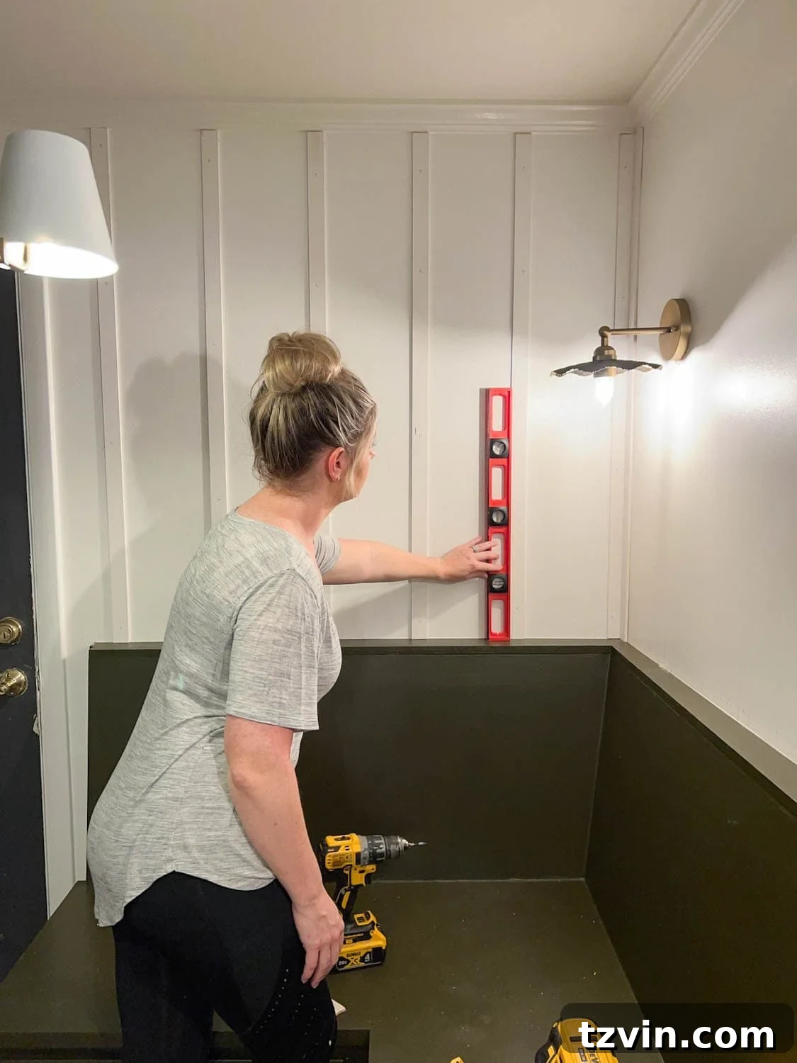 Create a Budget Batten Wall with Lattice Strips 6 A person using a long level to ensure a vertical lattice strip is perfectly perpendicular on the wall before nailing