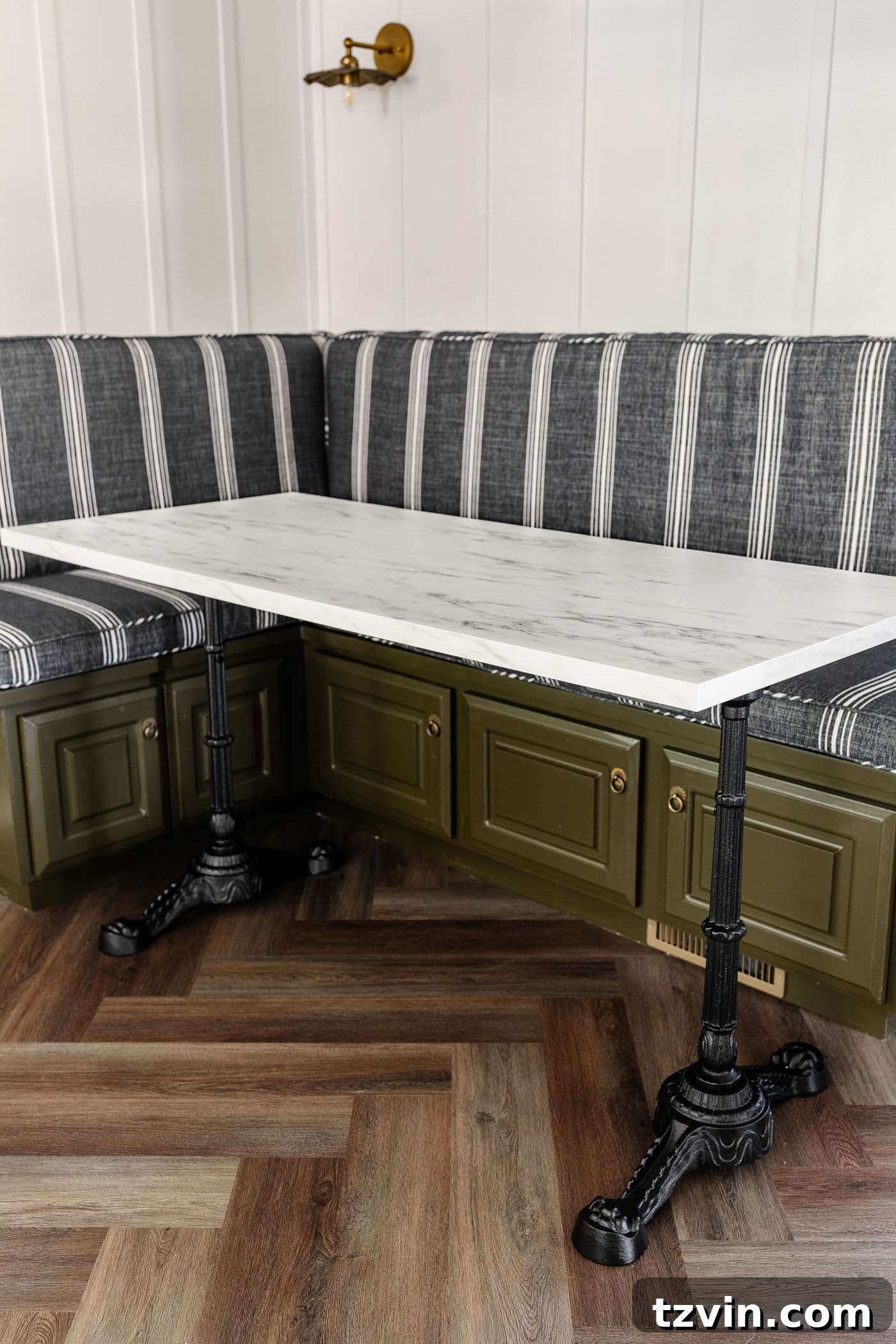 DIY Faux Marble Dining Table: Instant Luxury in Under an Hour 11 Parisian style faux marble dining table with cast iron pedestal legs against an olive green banquette with charcoal striped bench cushions and herringbone wood floors, highlighting the elegant finished look