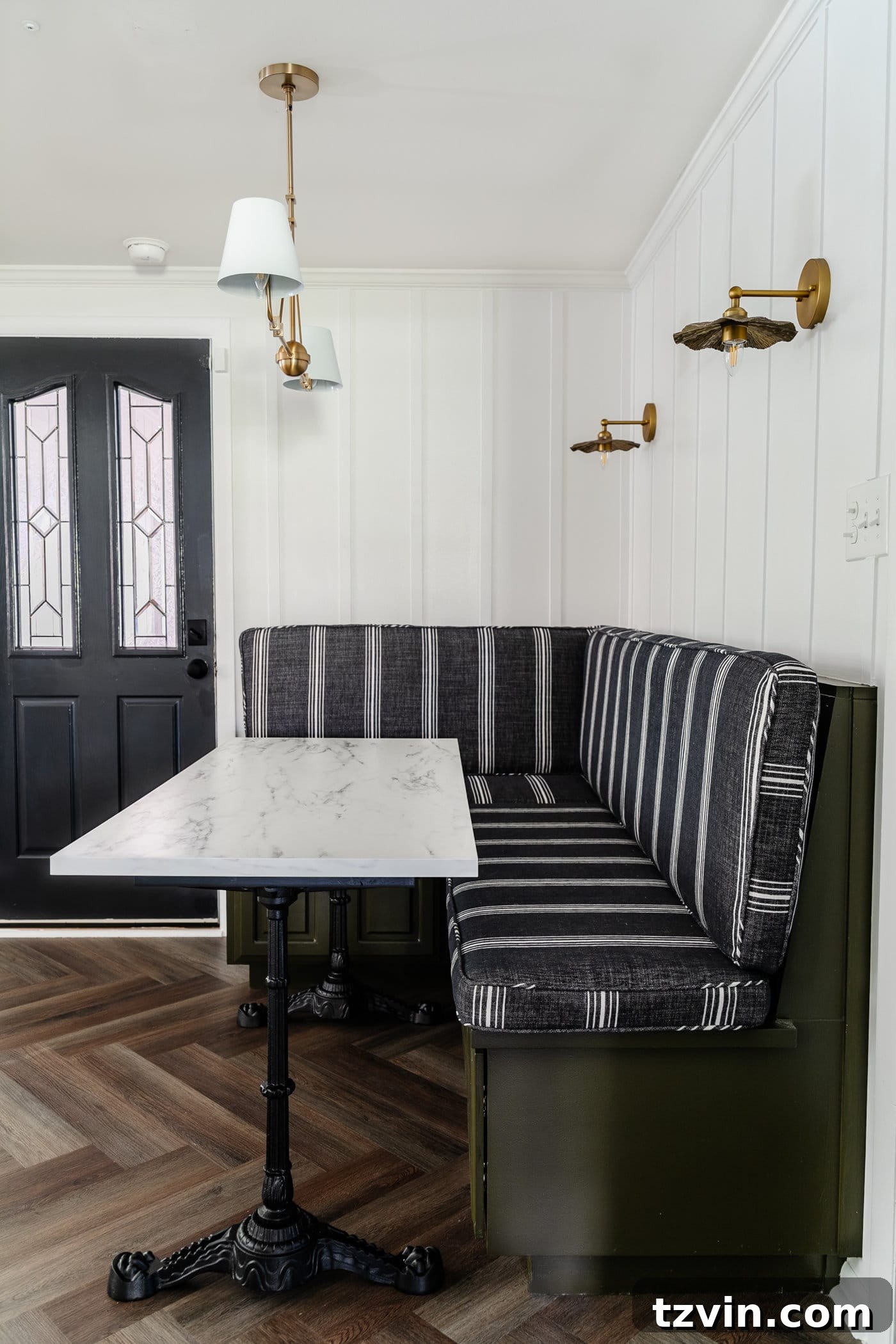 DIY Faux Marble Dining Table: Instant Luxury in Under an Hour 12 Parisian style faux marble dining table with cast iron pedestal legs against an olive green banquette with charcoal striped bench cushions and herringbone wood floors, showcasing the full breakfast nook design
