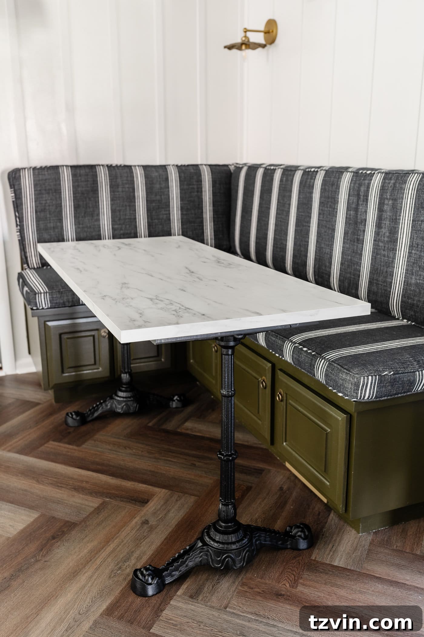 DIY Faux Marble Dining Table: Instant Luxury in Under an Hour 3 Parisian style faux marble dining table with cast iron pedestal legs against an olive green banquette with charcoal striped bench cushions and herringbone wood floors, showcasing custom fit and elegant design